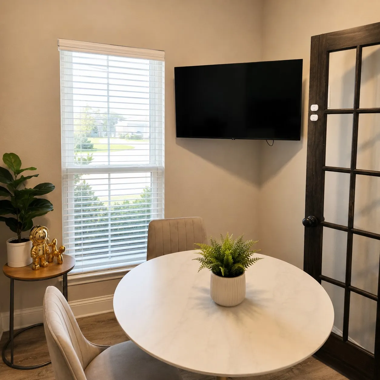 Wall-mounted television with a corner placement, wood-finish flooring, and a dark-toned interior door with glass​​‌​​​​‌​​‌‌​‌‌​​​‌‌​‌​‌​‌​​​‌​​ panes