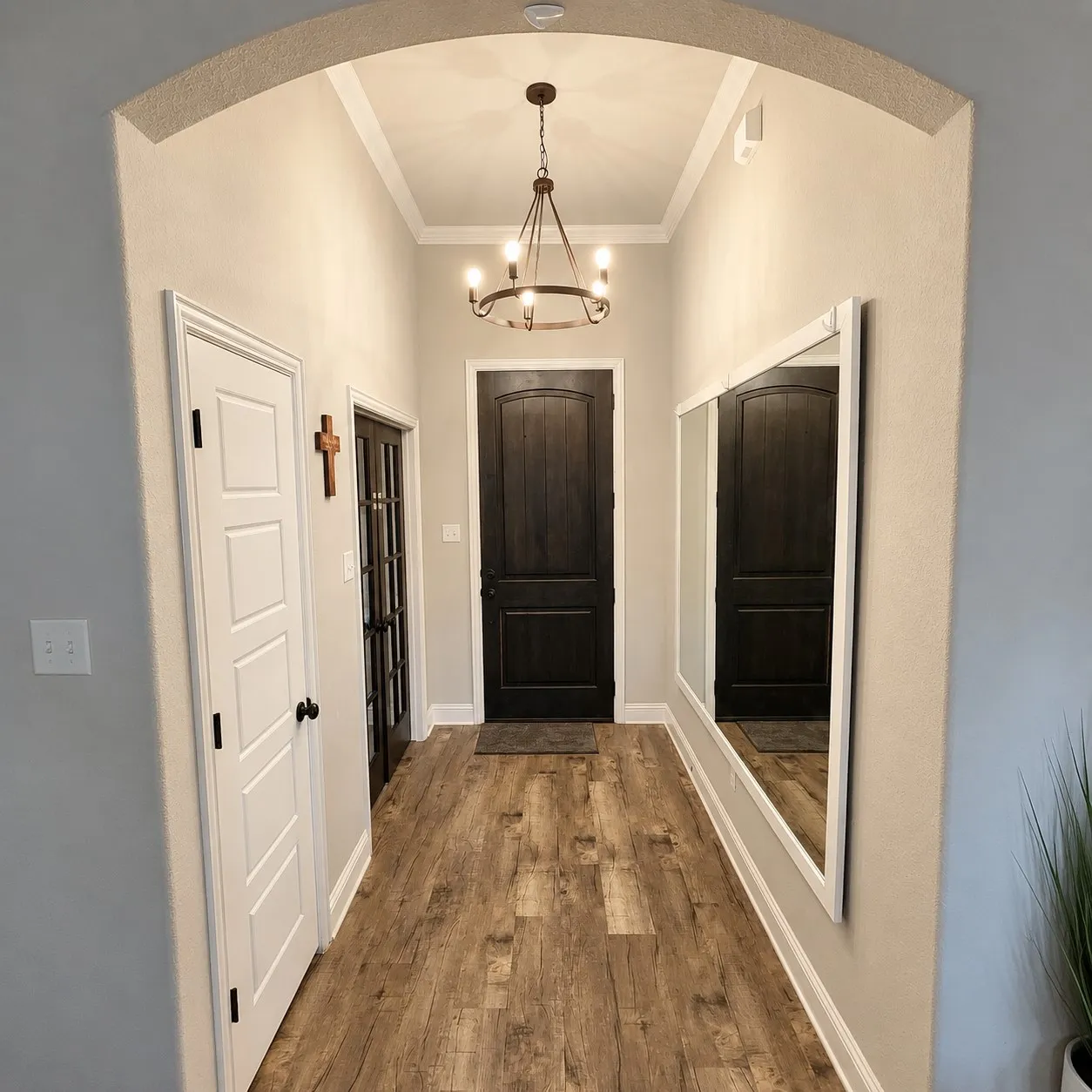 Arched entryway featuring wood-finish flooring, dark paneled doors, and a decorative chandelier