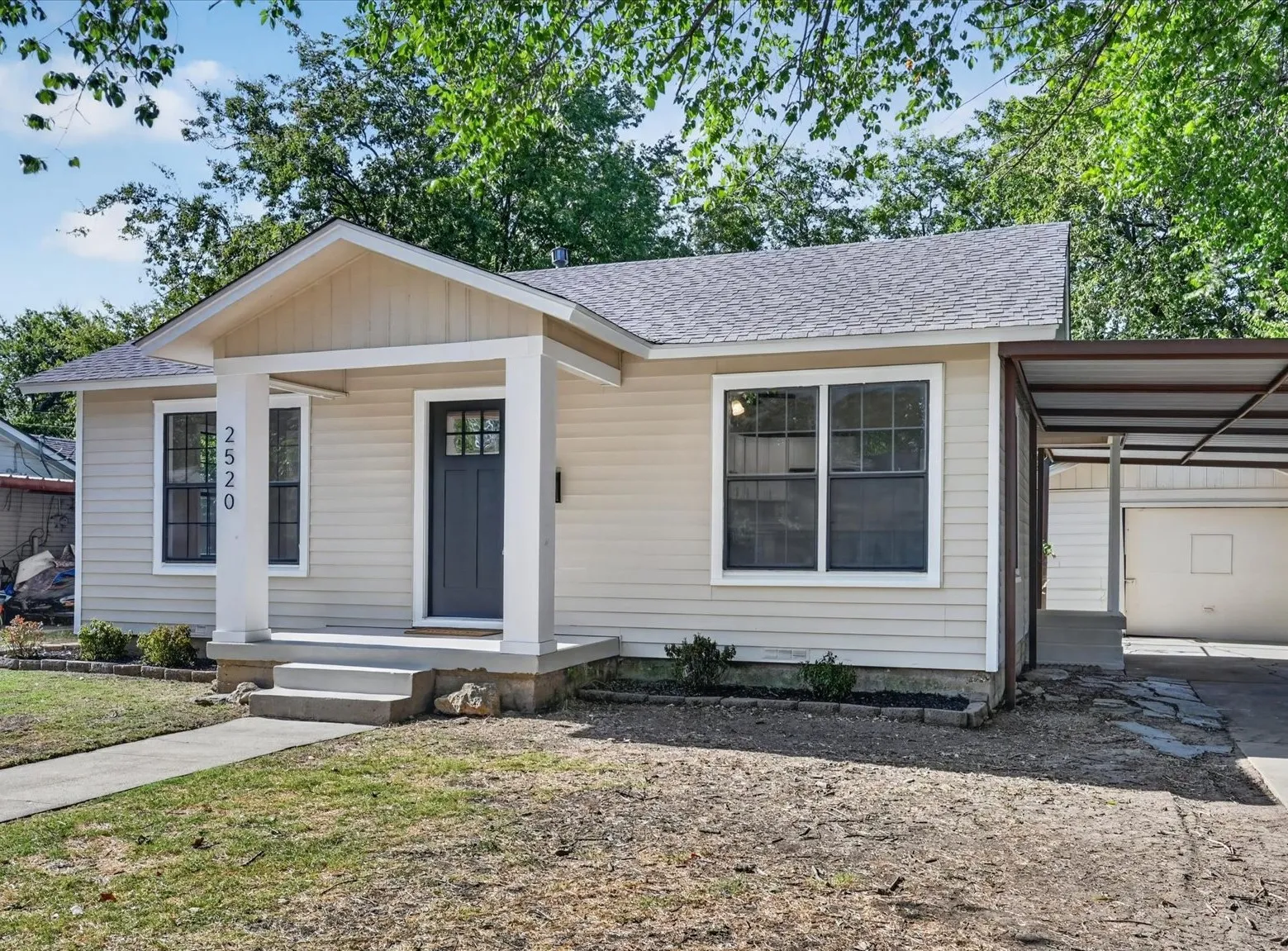 Siding exterior with a covered front porch, dark front door with window accents, and multiple windows with dark framing