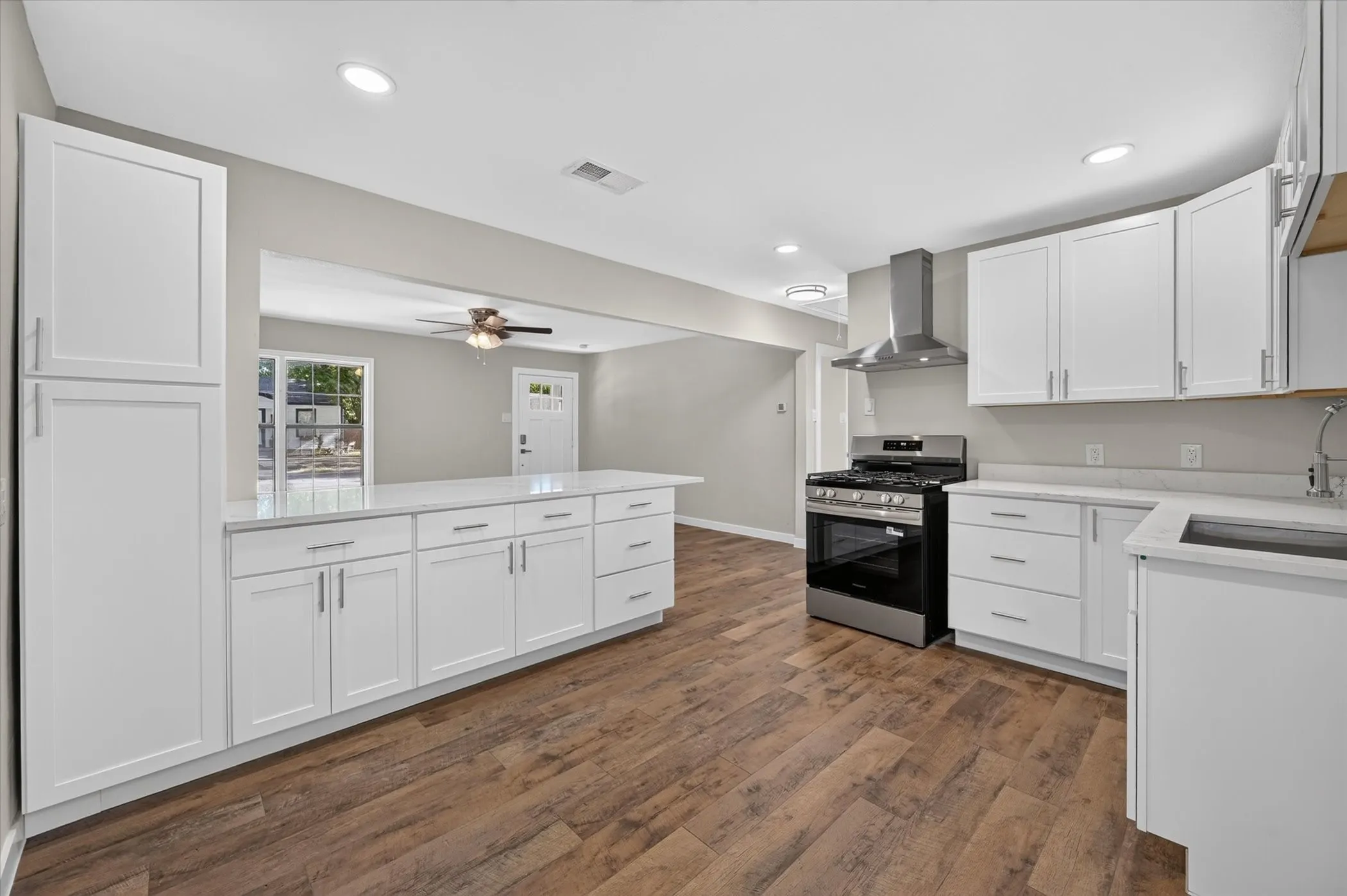Kitchen featuring white cabinetry, light-toned countertops, wood-finish flooring, recessed lighting, and stainless steel appliances