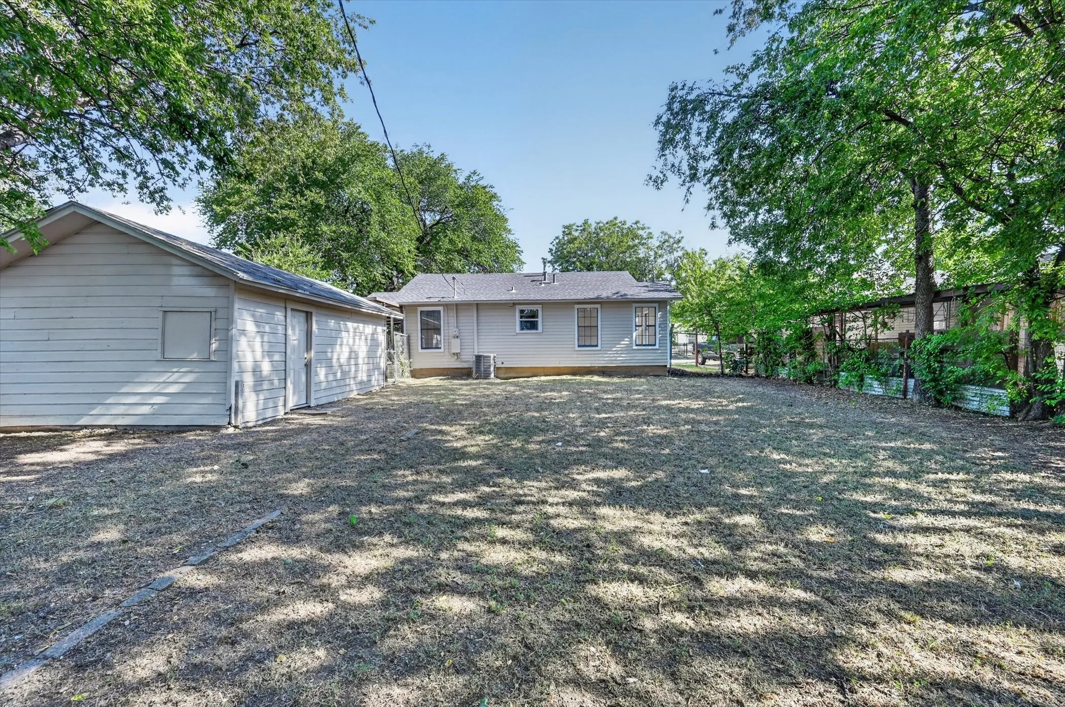Expansive backyard with a detached auxiliary structure, mature trees, and a private rear exterior