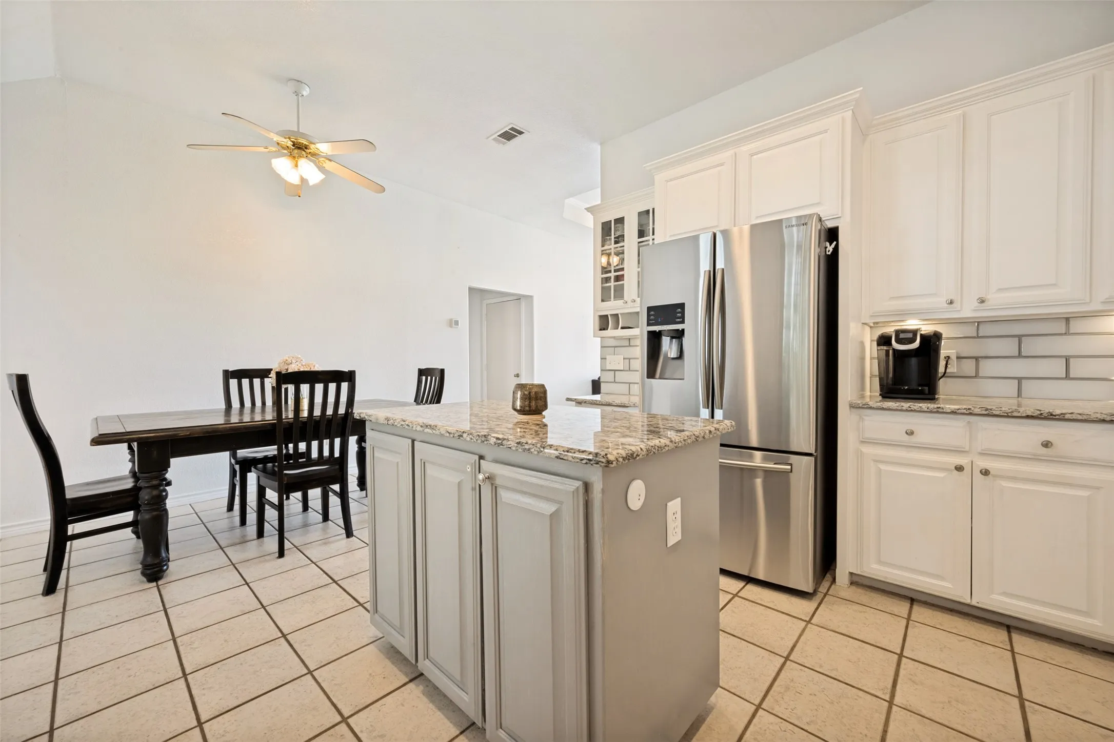 Kitchen featuring white shaker-style cabinetry, a subway tile backsplash, and granite countertops