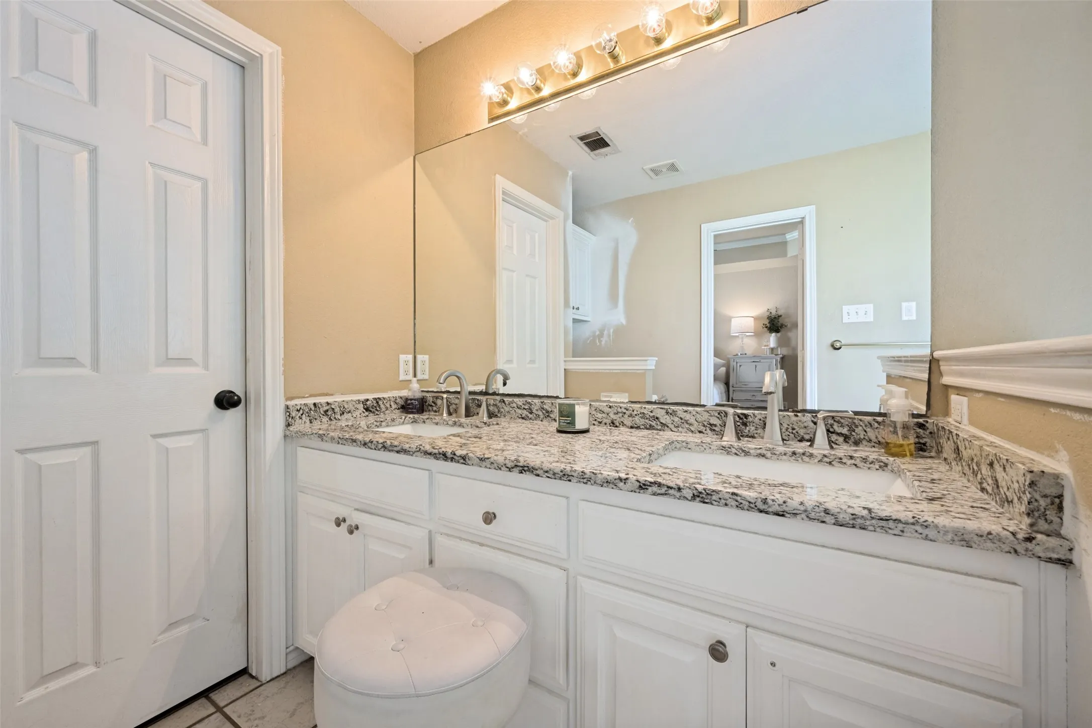Dual-sink vanity with a light-toned countertop and white cabinetry