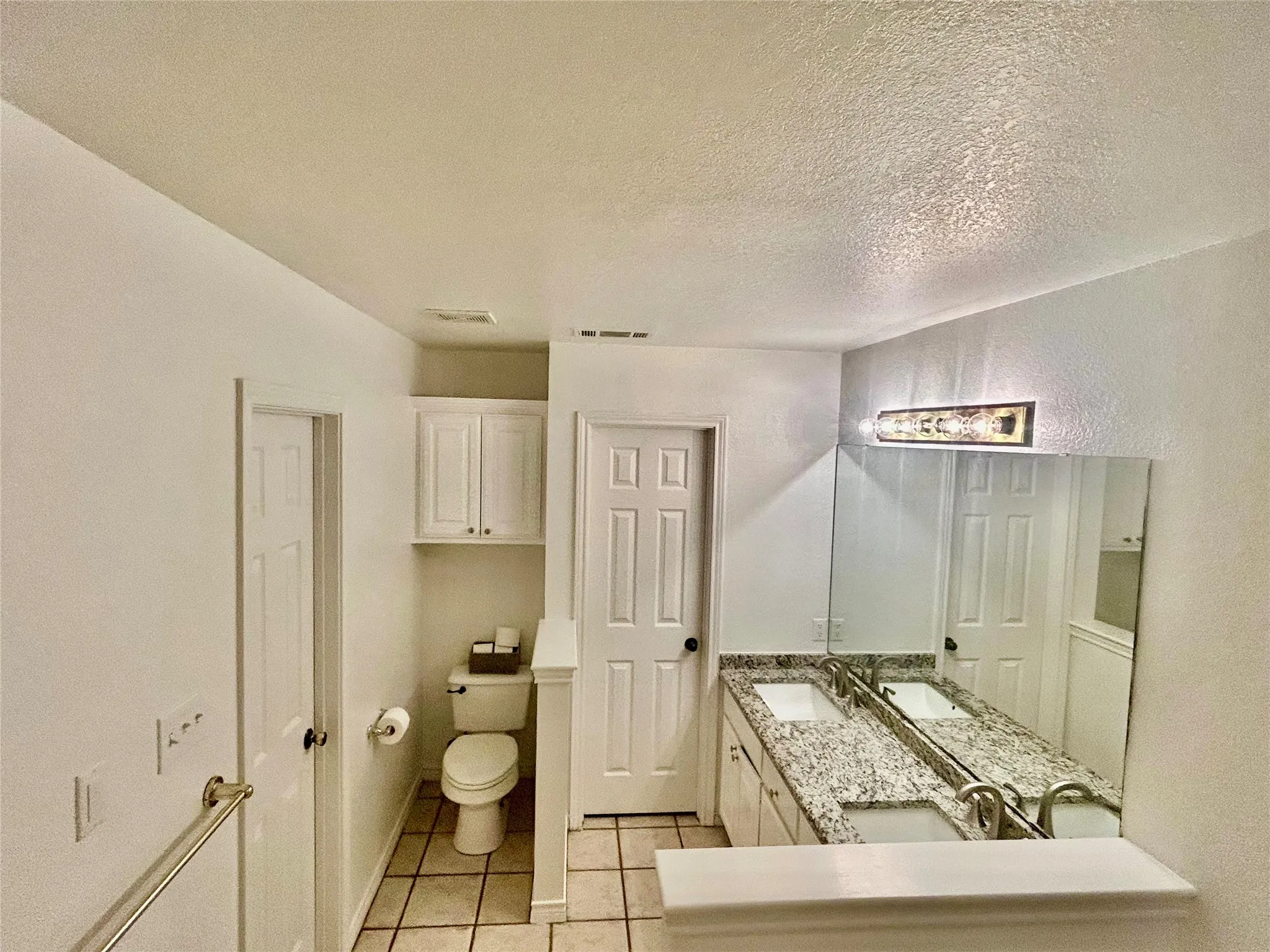 Dual vanity with granite countertops, integrated sinks, and polished chrome fixtures
