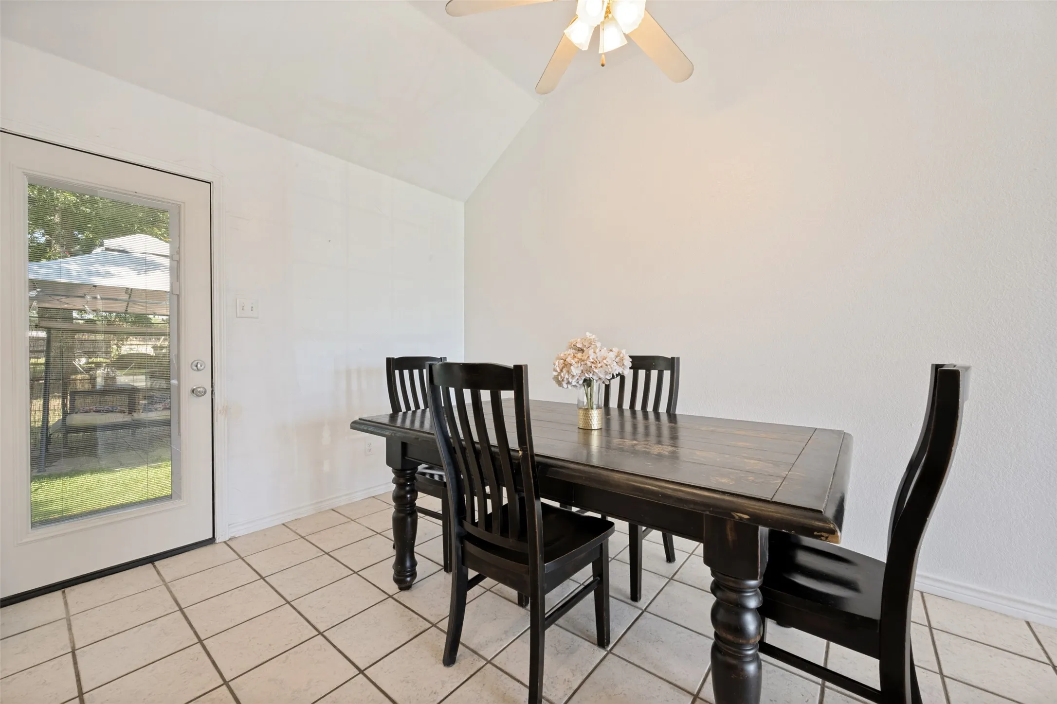 Vaulted ceiling, ceiling fan, full-light door, tiled flooring, textured walls