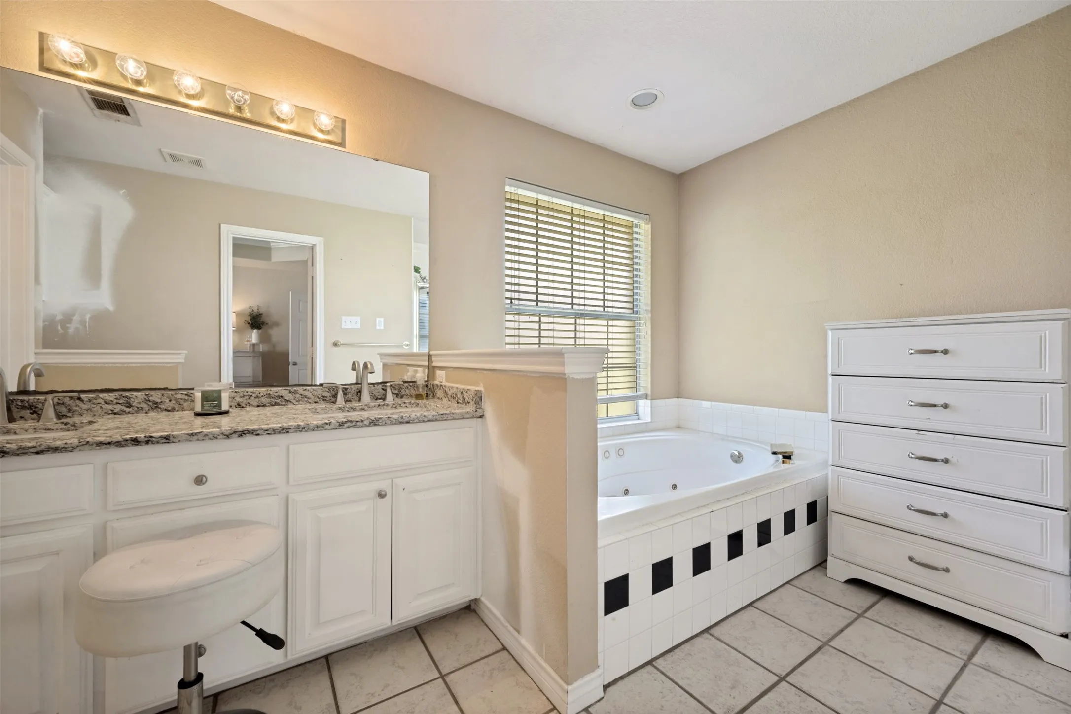 Dual vanity with polished chrome fixtures, integrated jetted bathtub, tiled flooring, window with blinds, and recessed lighting