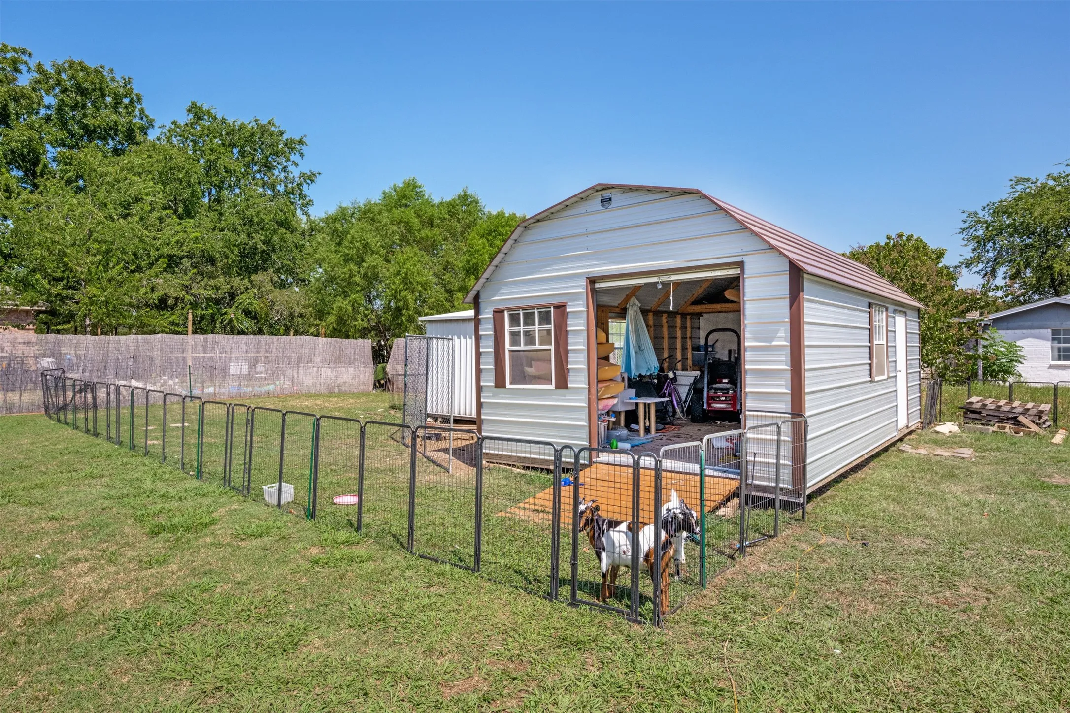 Detached metal structure with a roll-up door, side entry, and fenced enclosure