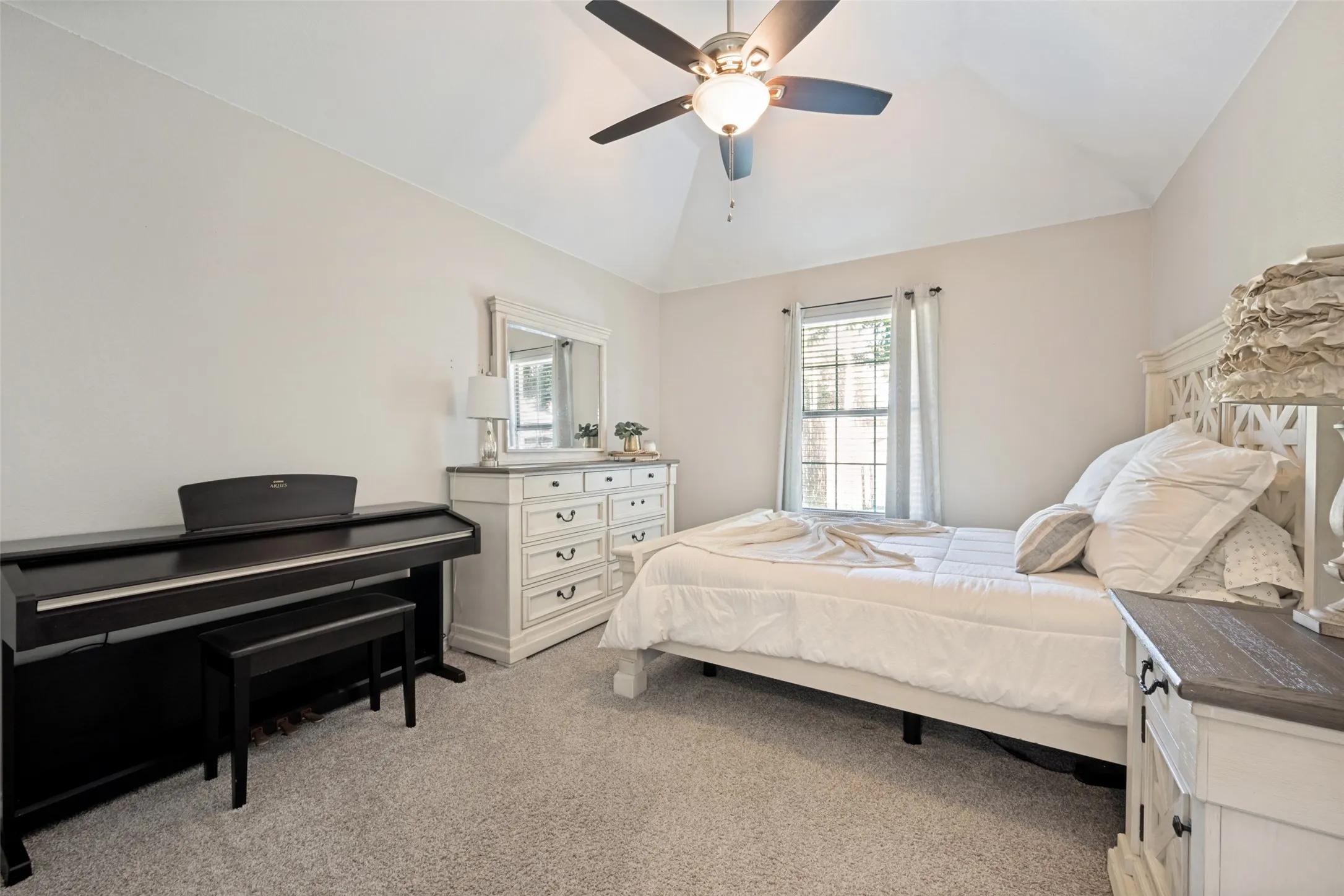 Vaulted ceiling with ceiling fan, window with natural light, and carpeted flooring
