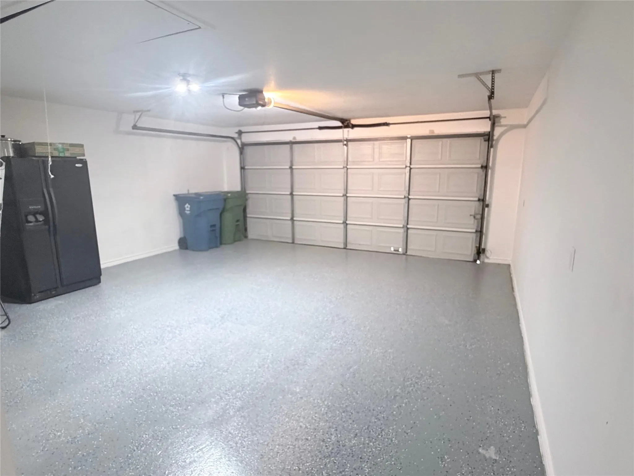 Spacious garage with an overhead door, automatic opener, and a speckled epoxy floor finish