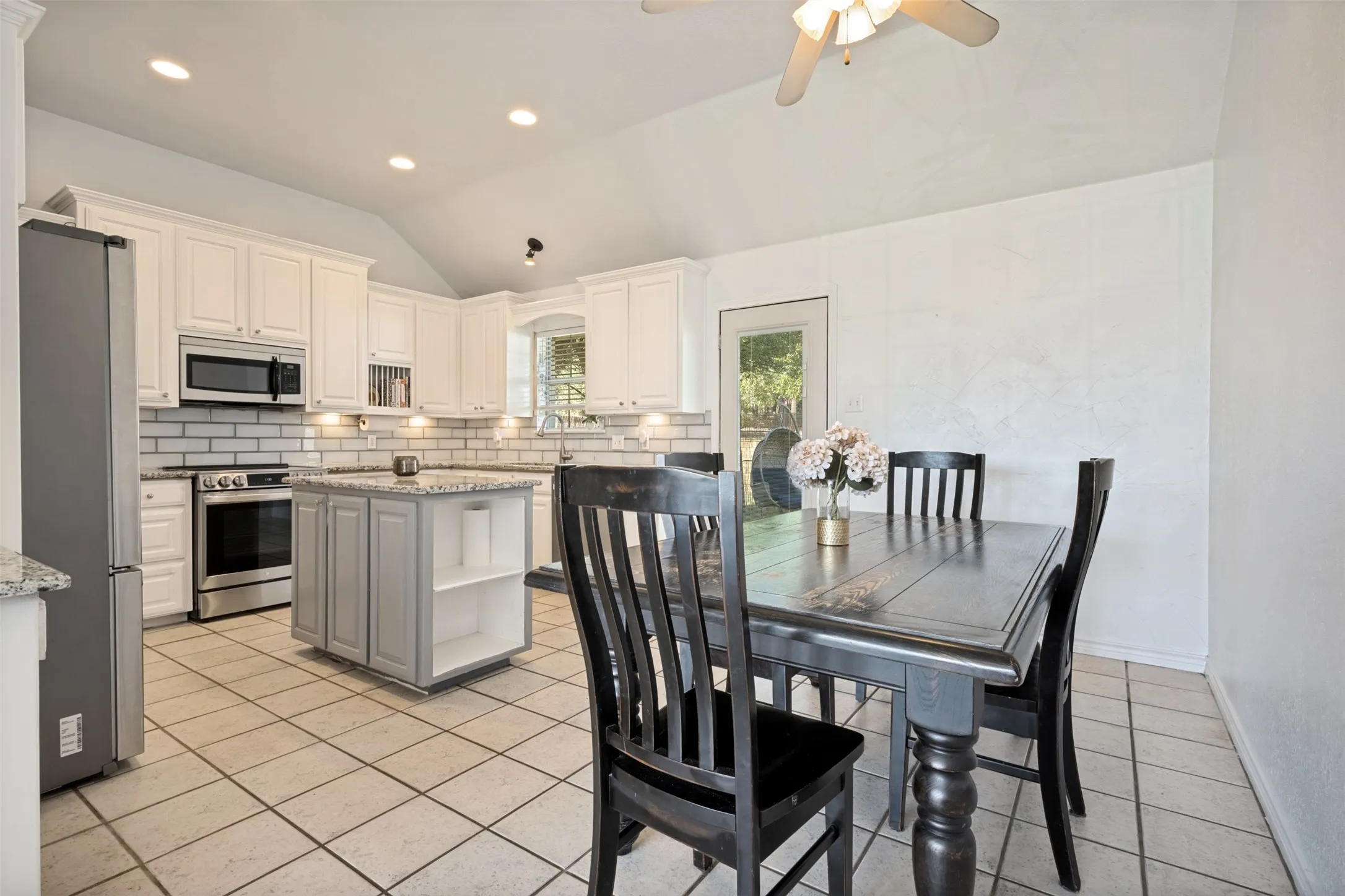 Kitchen featuring white cabinetry, subway tile backsplash, stainless steel appliances, a center island with open shelving, and tile flooring