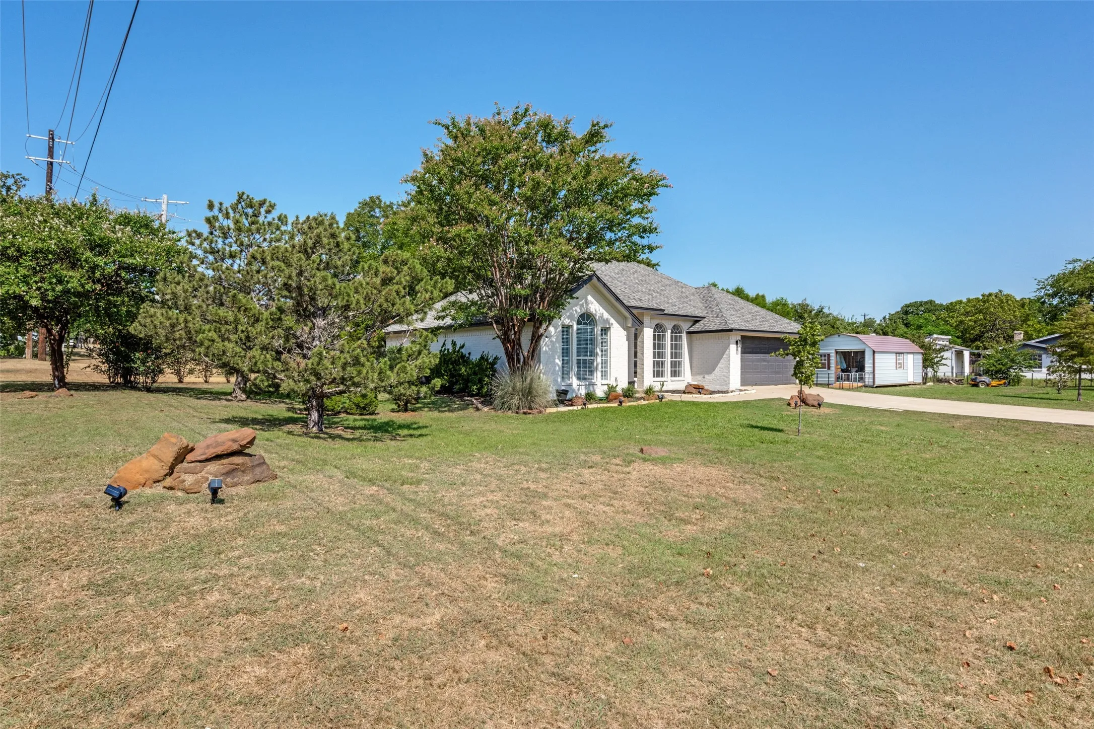 White exterior with arched windows, attached garage, and a long driveway