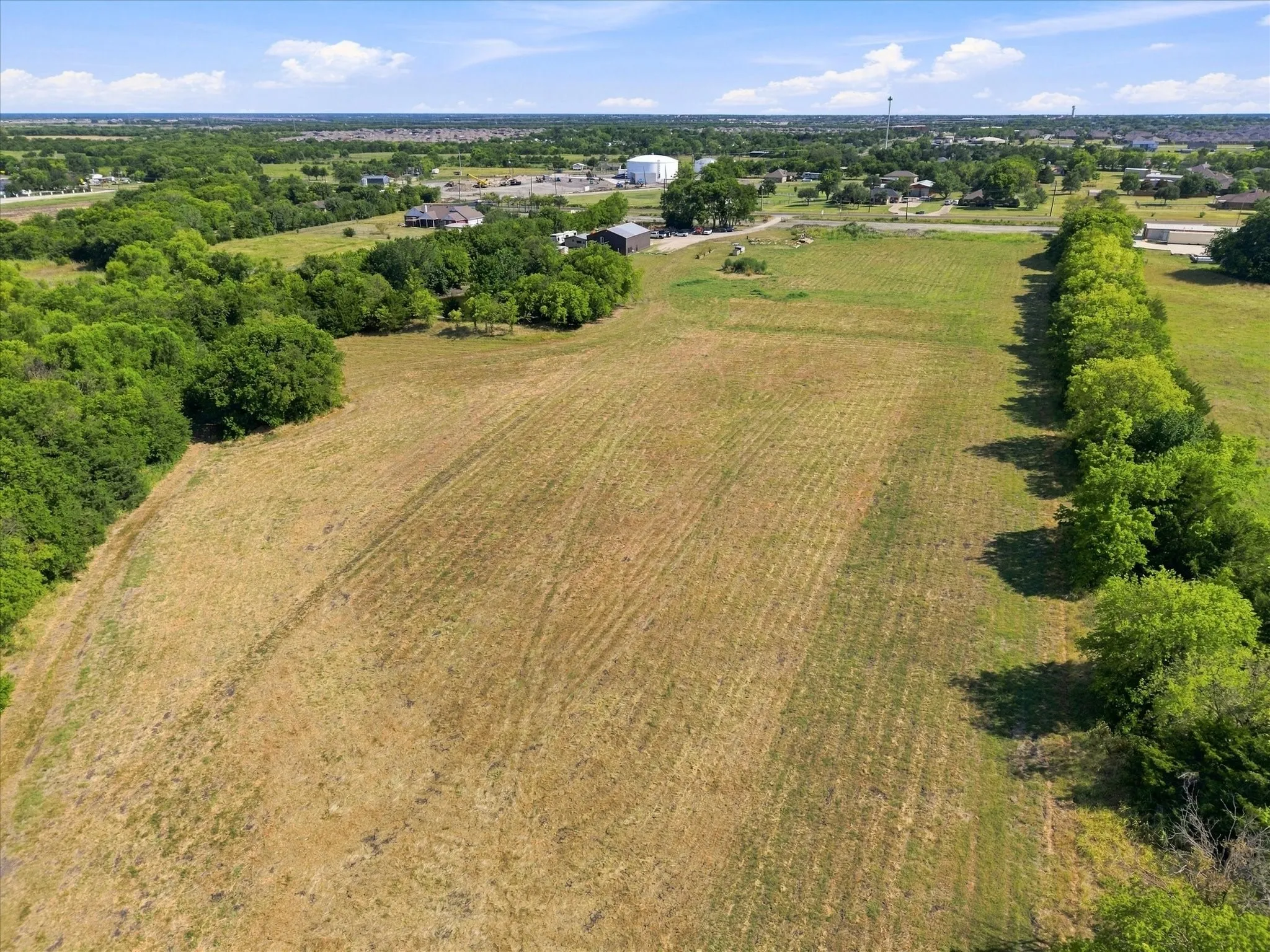 Expansive land parcel featuring open fields and mature tree lines