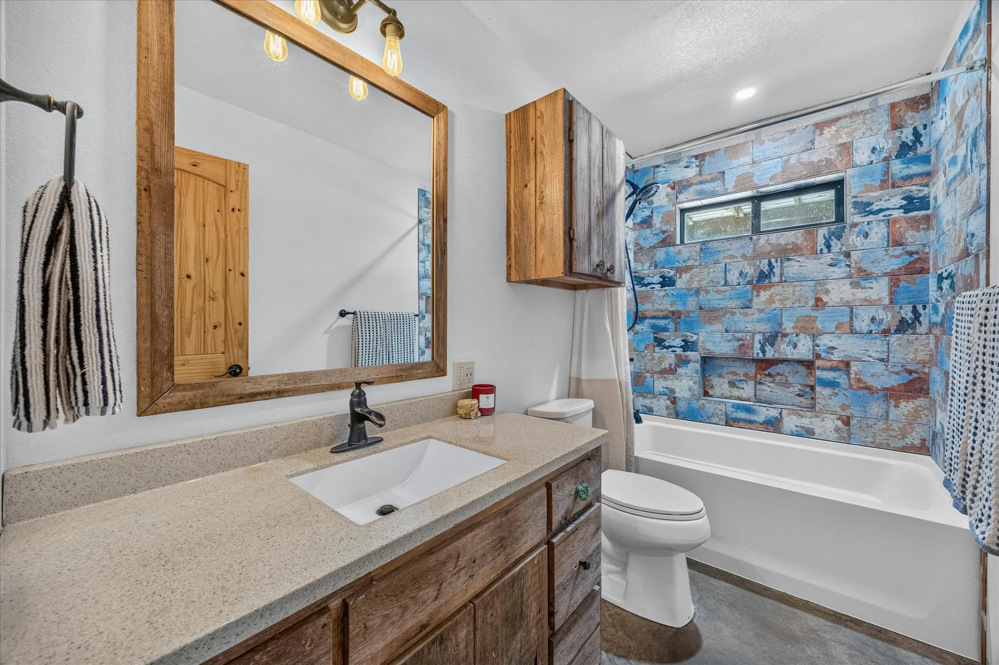 Bathroom featuring a vanity with wood-finish cabinetry, a stone-finish countertop, and an undermount sink