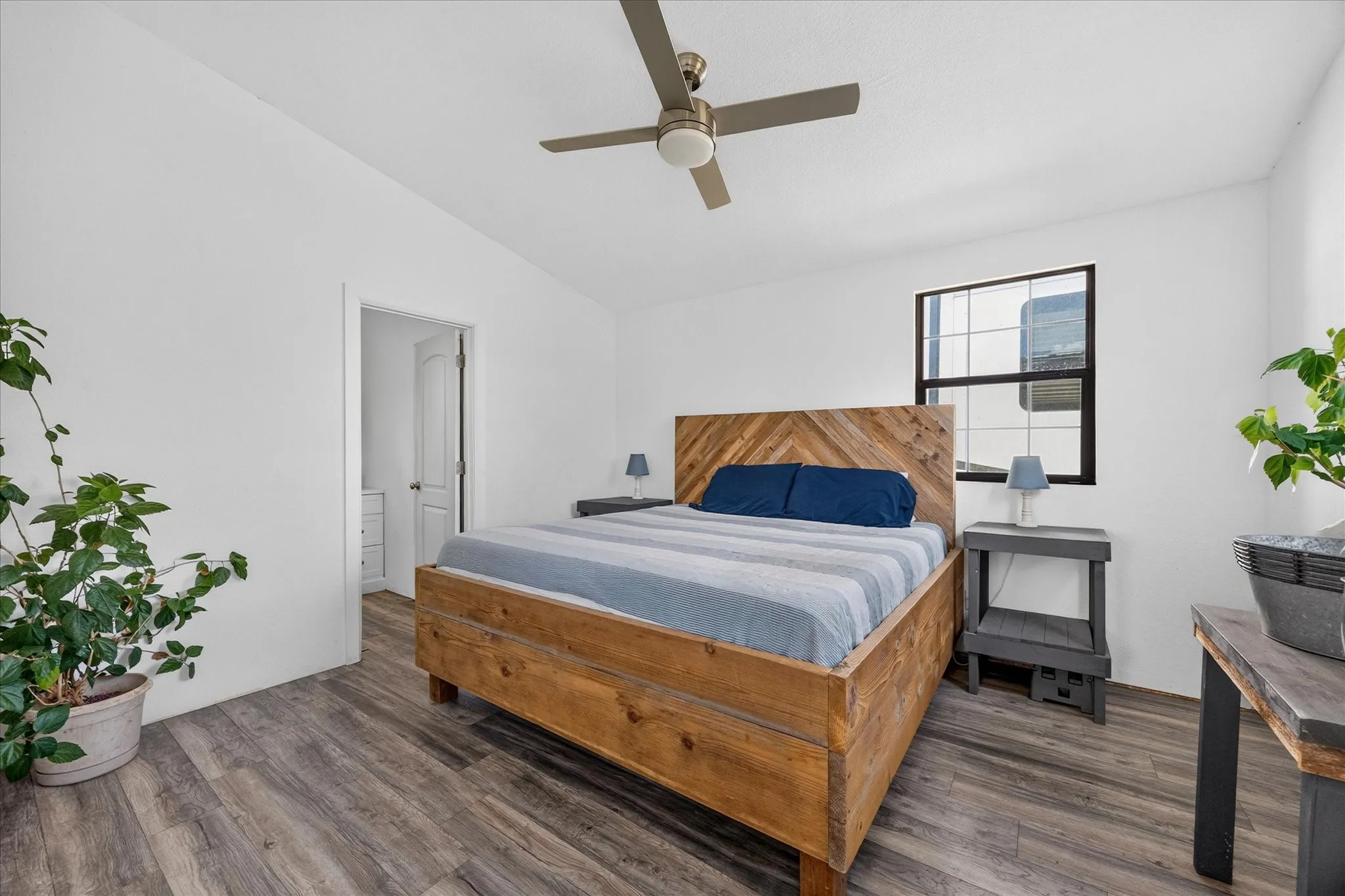 Wood-finish flooring, white walls, and a ceiling fan with integrated lighting