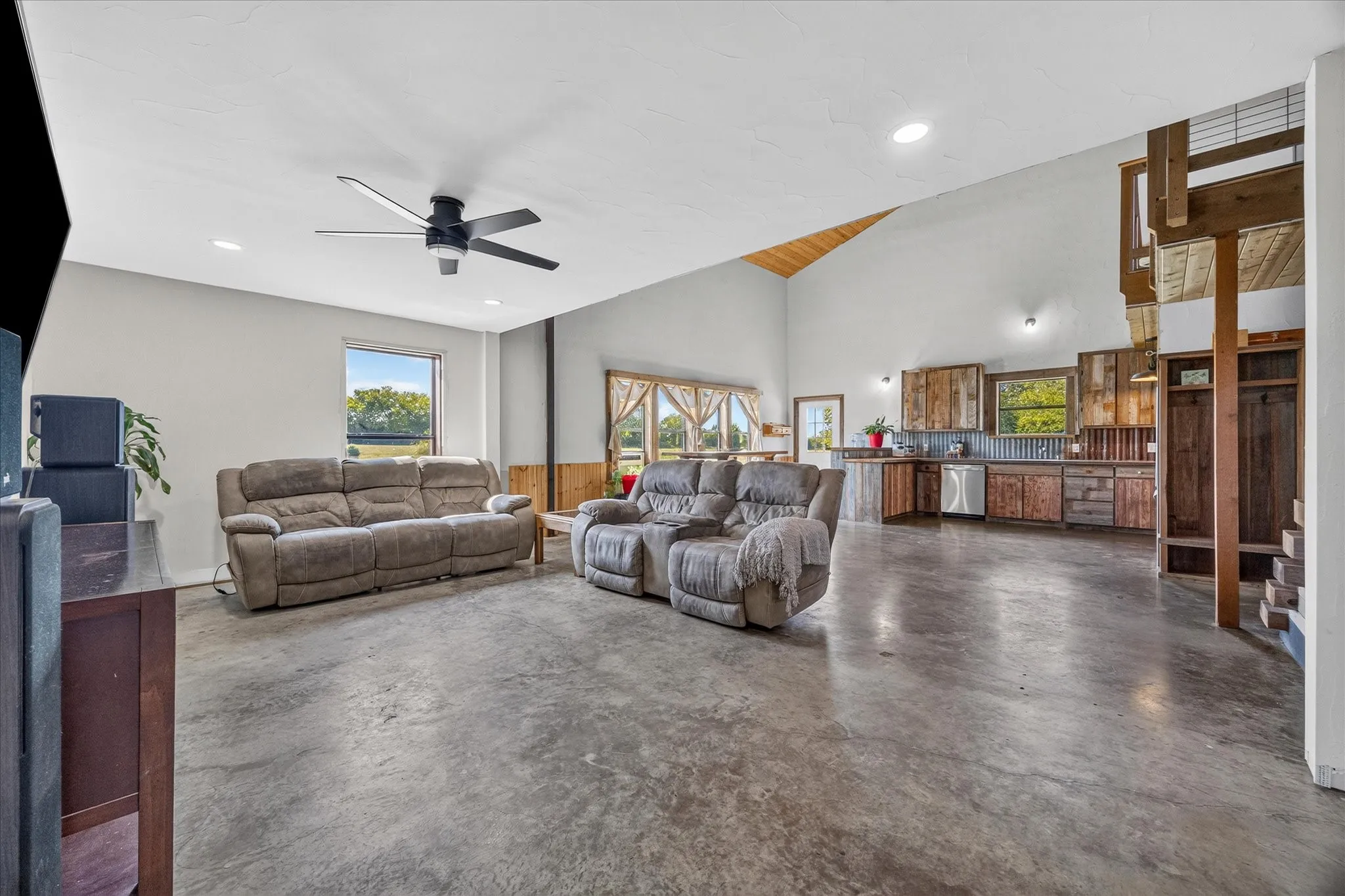 Vaulted ceiling with exposed wood beams, polished concrete flooring, recessed lighting, and a modern ceiling fan