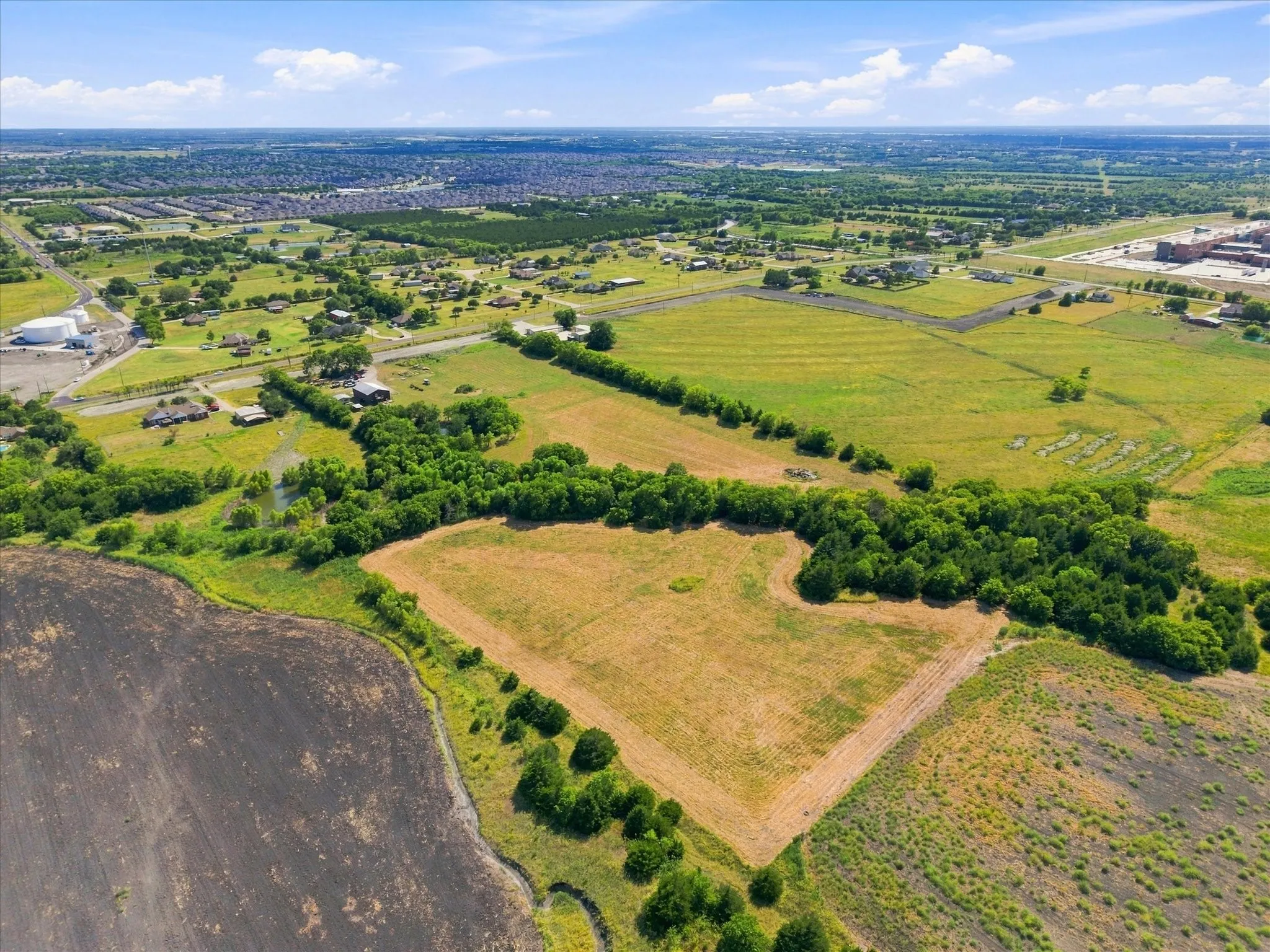 Expansive land parcel featuring open fields, scattered mature trees, and natural vegetation