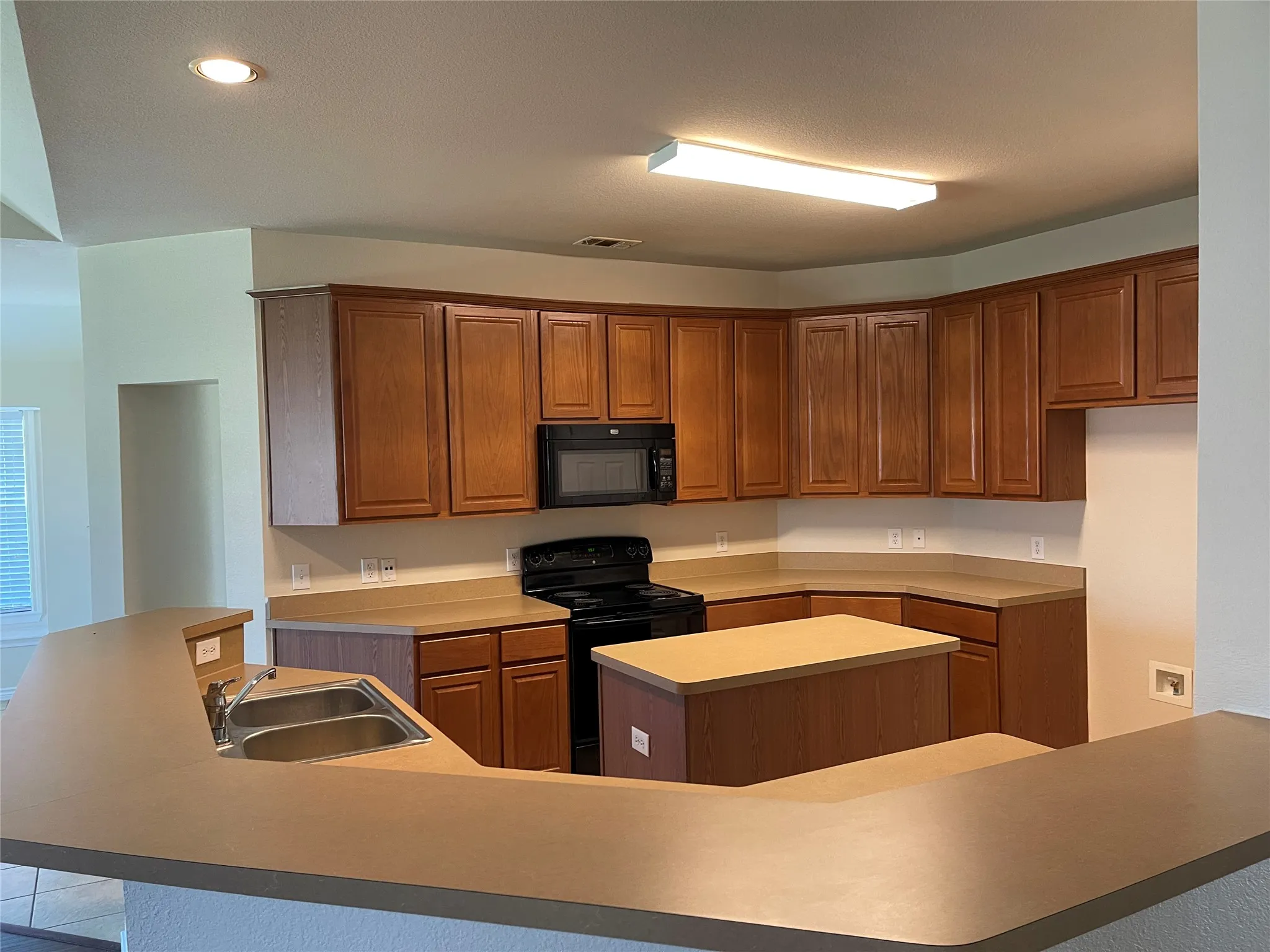 Kitchen with an island with sink, sink, and black appliances