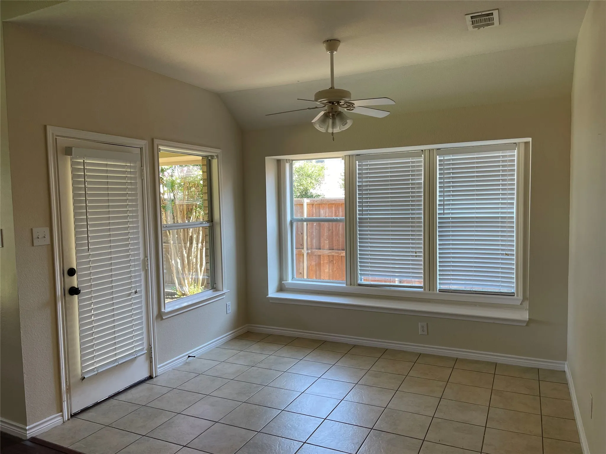 Empty room featuring ceiling fan, light tile flooring, and lofted ceiling