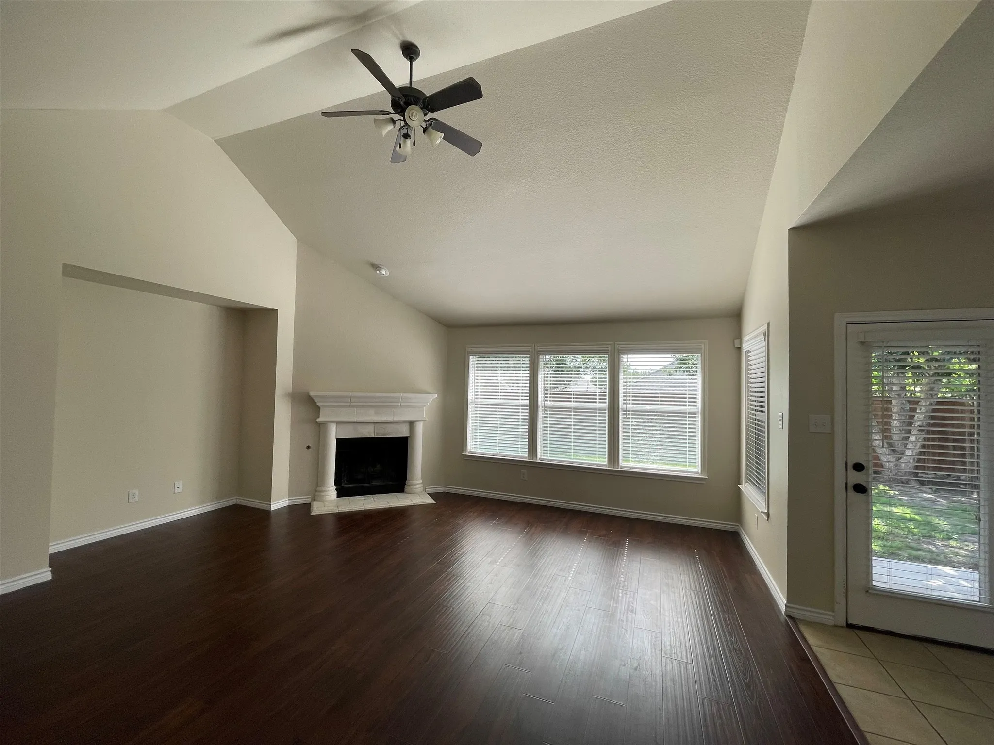 Unfurnished living room with a healthy amount of sunlight, wood-type flooring, ceiling fan, and vaulted ceiling