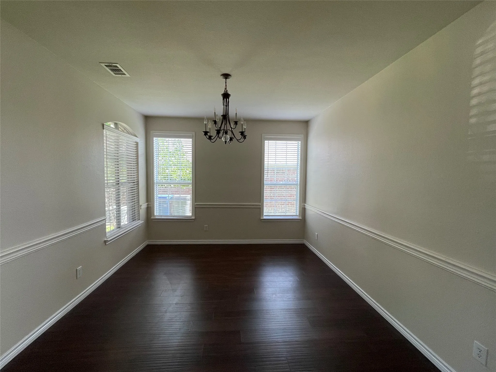 Spare room featuring an inviting chandelier and hardwood / wood-style floors