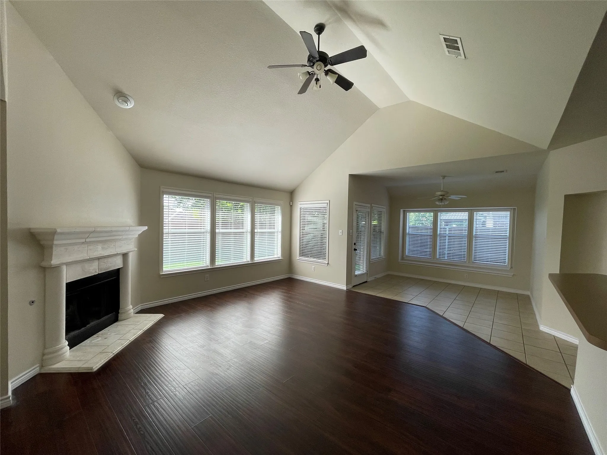 Unfurnished living room with tile floors, ceiling fan, a fireplace, and lofted ceiling