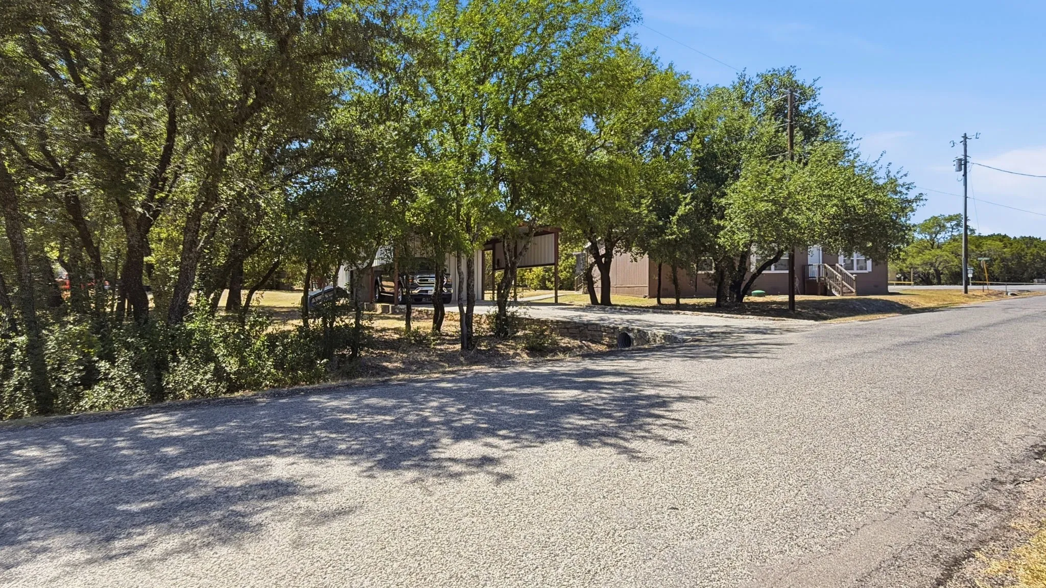 Side view of carport and corner lot with trees