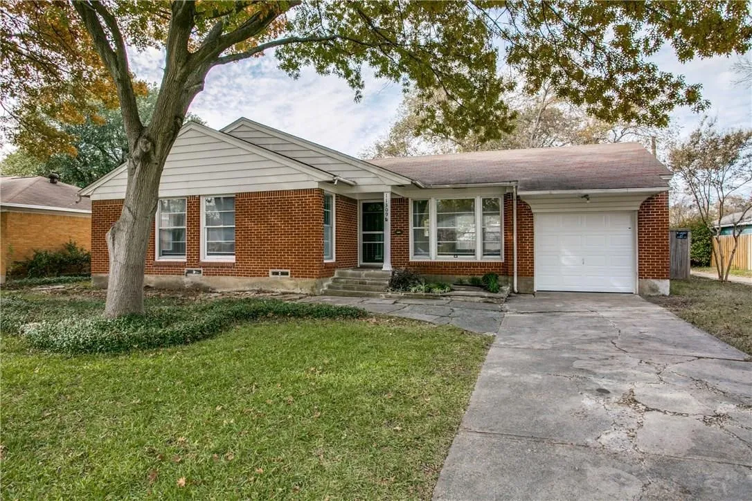 Brick exterior with white siding accents, an attached garage, and a concrete driveway
