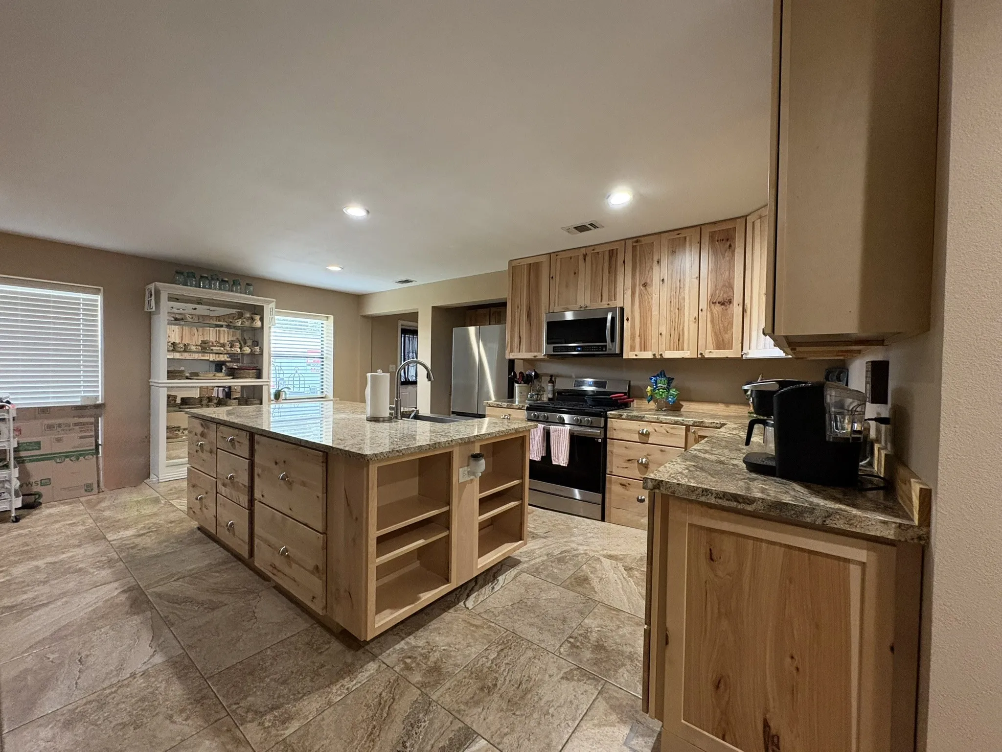 Kitchen featuring natural wood cabinetry, stainless steel appliances, granite countertops, and tile flooring