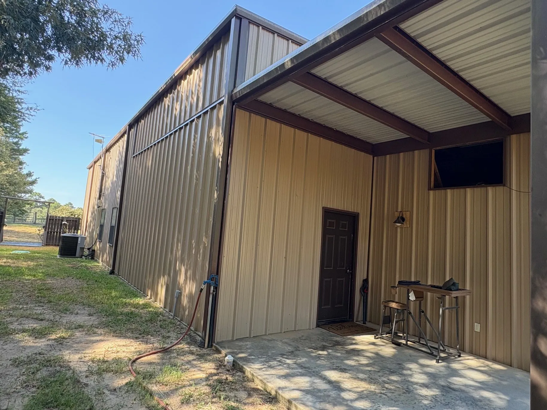 Modern metal-clad structure featuring a gabled roof design, covered porch entry with metal railings, and corrugated steel siding