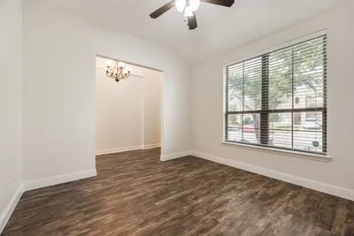 Wood-finish flooring, vaulted ceiling, ceiling fan, large window with blinds, and an arched entry