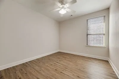 Wood-finish flooring, white walls, and a window with blinds