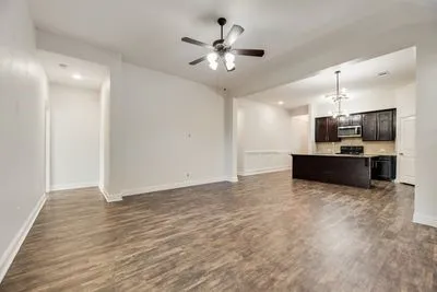 Open-concept living space featuring wood-finish flooring, a ceiling fan, recessed lighting, and a kitchen with dark cabinetry and stainless steel appliances