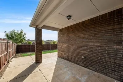 Covered concrete patio with a brick column and a fixed light fixture
