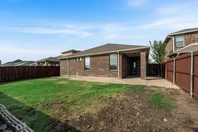 Brick exterior with covered patio, concrete pathways, and wood privacy fencing