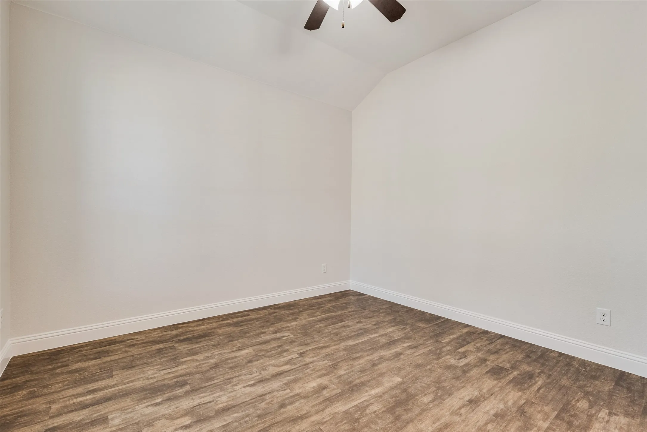 Vaulted ceiling with a ceiling fan, wood-finish flooring, and white walls