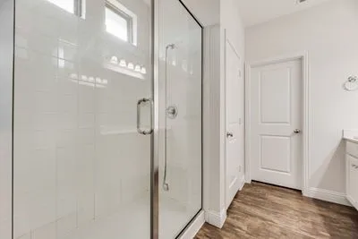 Glass-enclosed shower with white tiled walls and transom windows