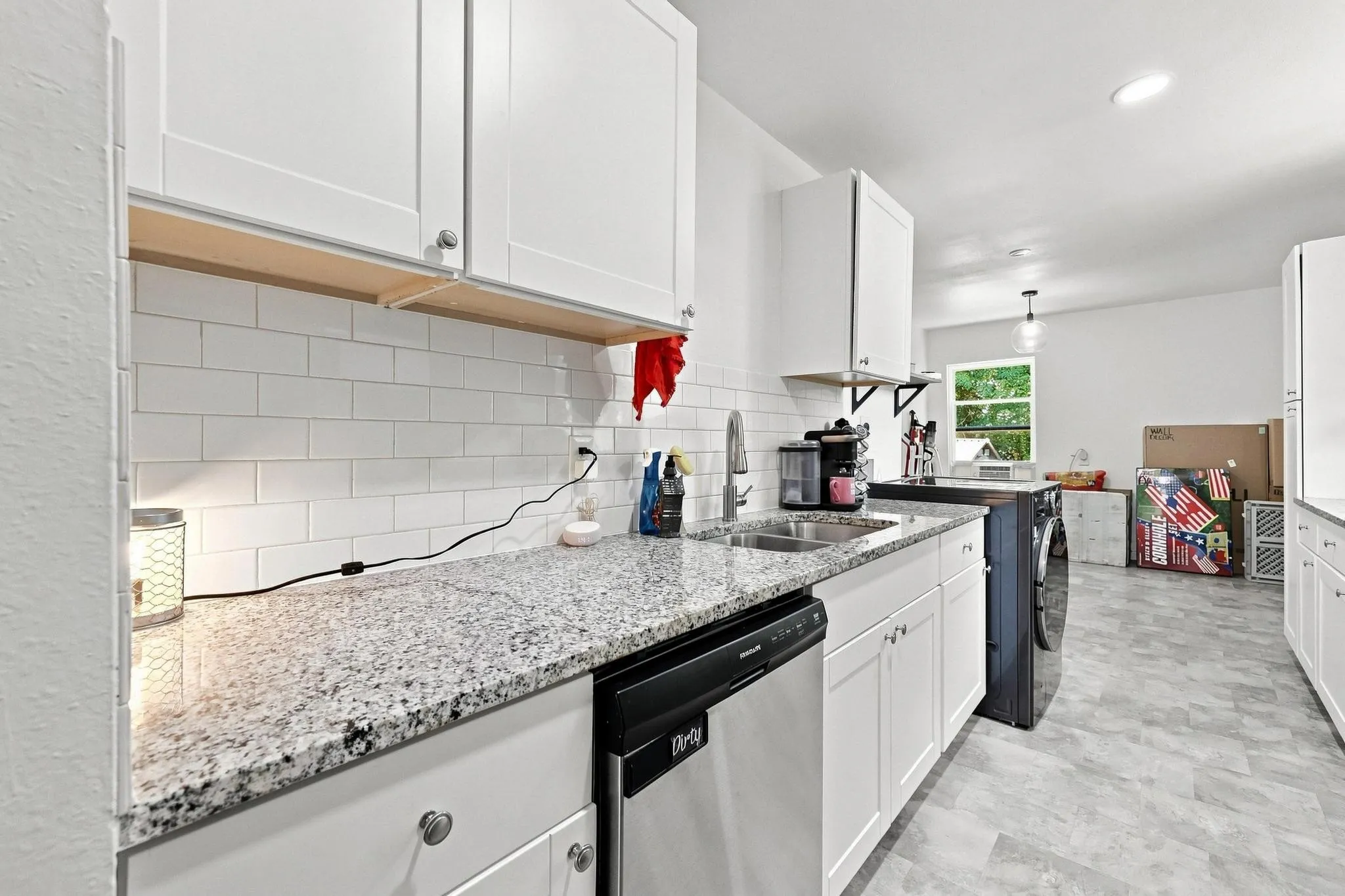 White shaker cabinetry, subway tile backsplash, speckled countertops, and stainless steel dishwasher