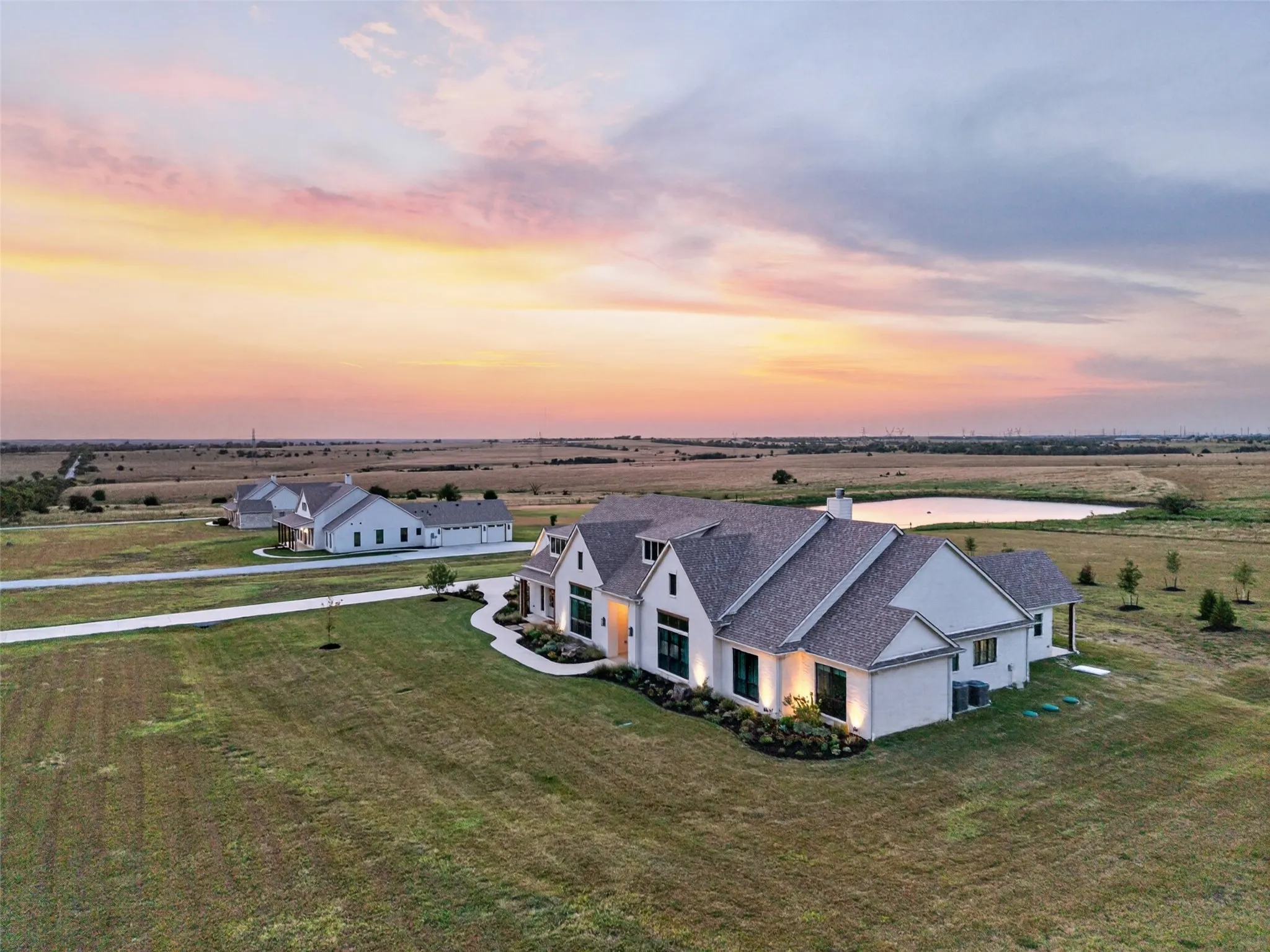 Modern farmhouse architecture featuring a light-colored exterior, gabled rooflines, and a concrete driveway