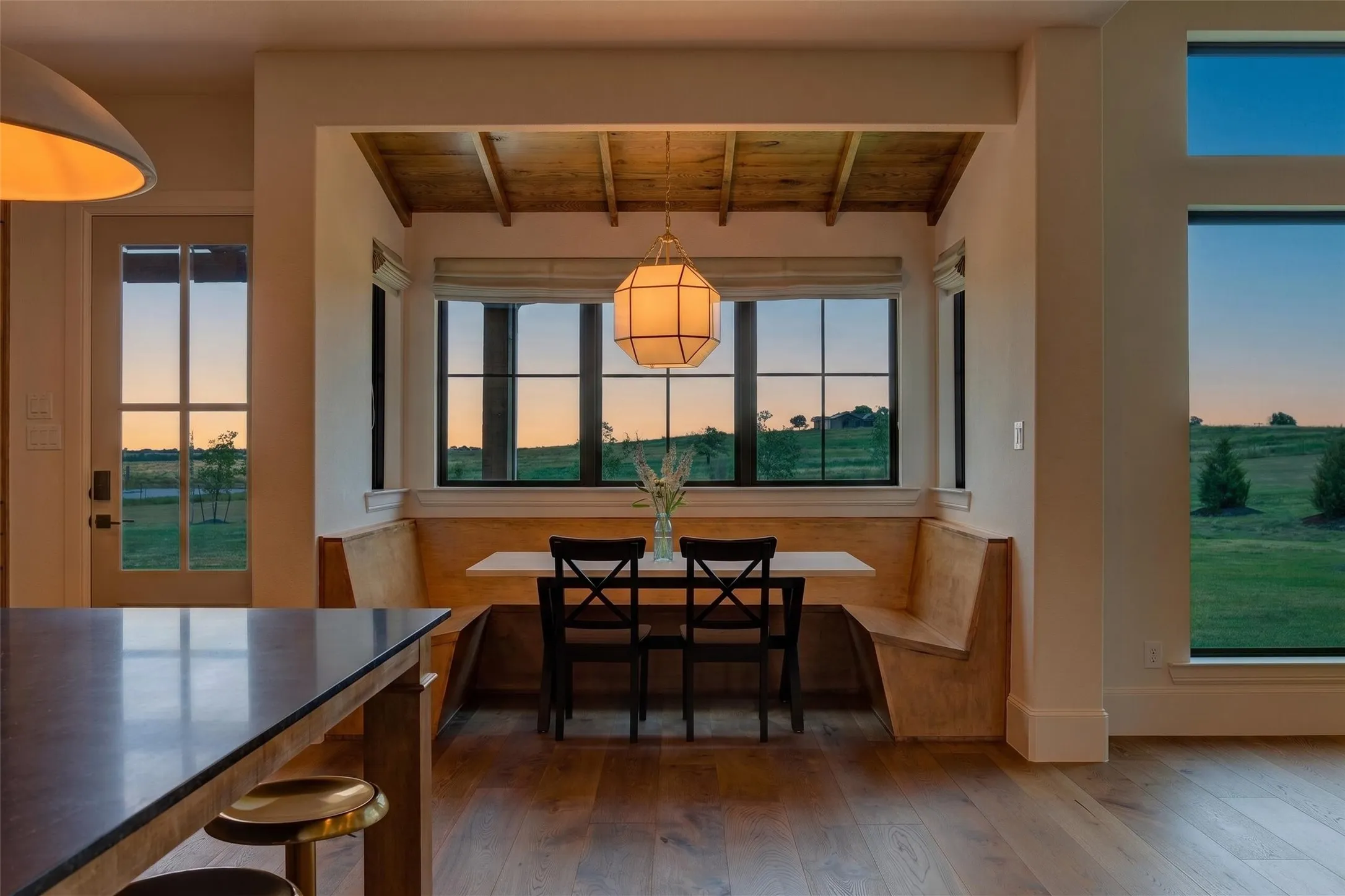 Built-in dining nook with wood-finish flooring, black-framed windows, and a coffered wood ceiling