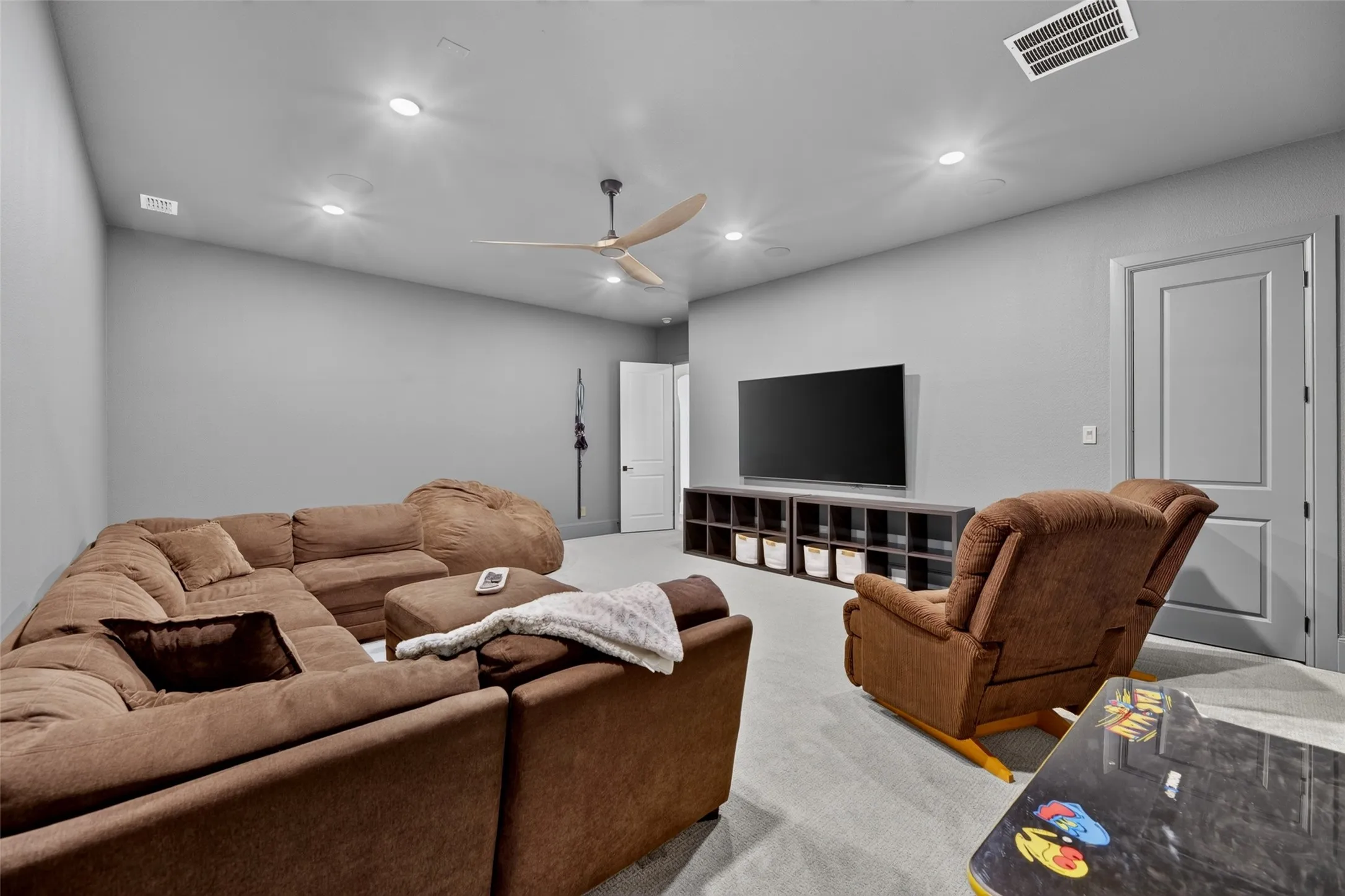 Recessed ceiling lighting, sloped ceiling, ceiling fan, wall-mounted television, and built-in storage units