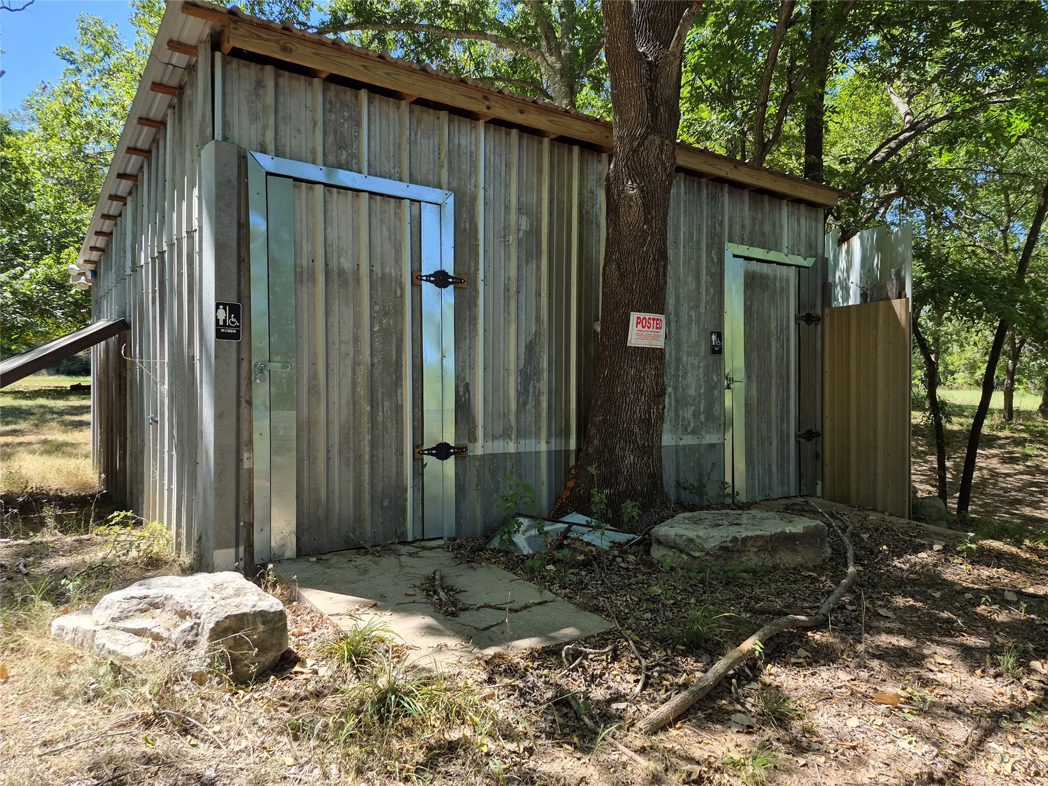 Corrugated metal siding structure with wood beam roof framing, featuring two entry doors with metal trim and integrated signage