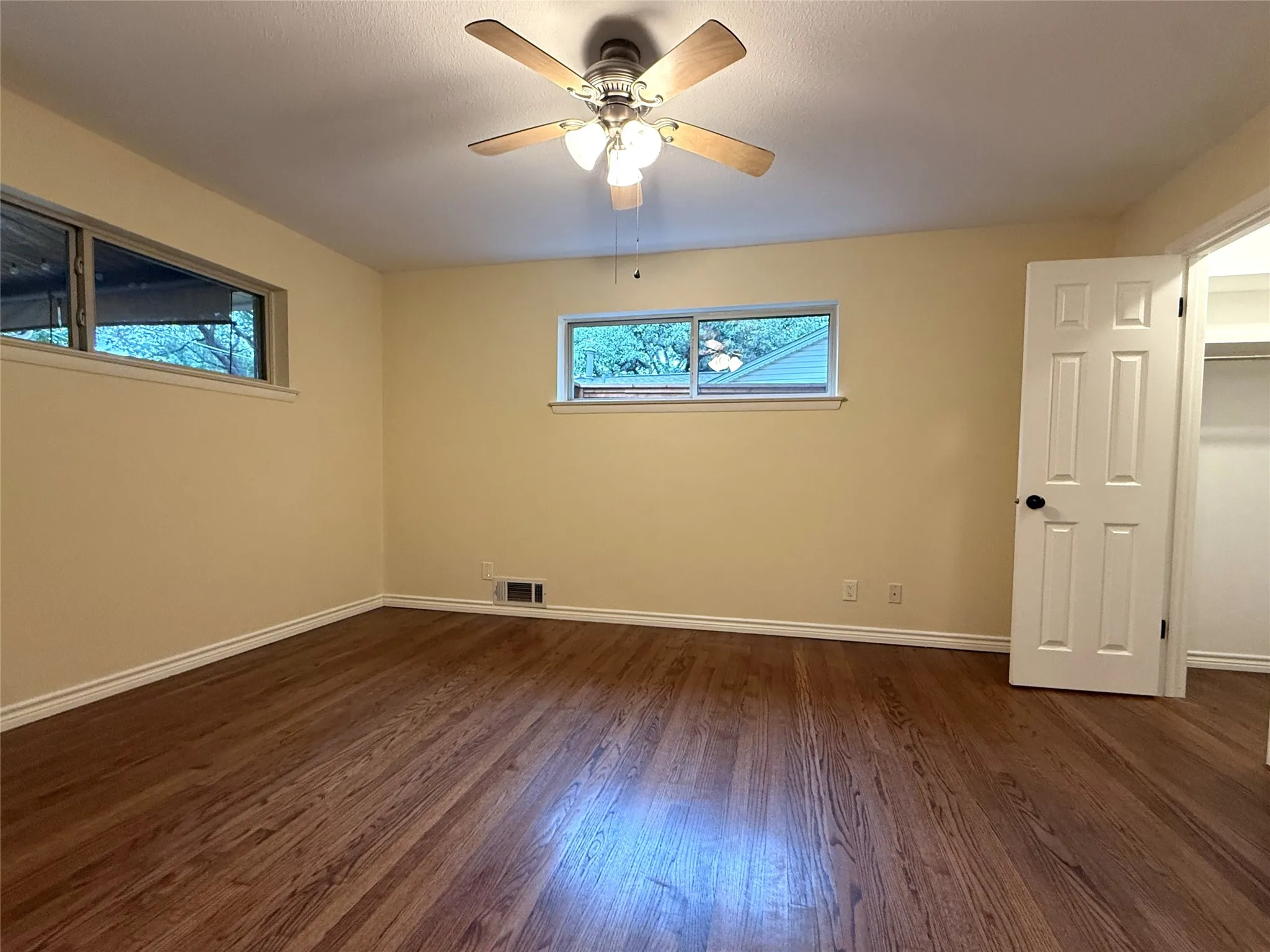 The primary bedroom is located at the back of the house, with windows welcoming the morning light and a view of the roses in the back yard.