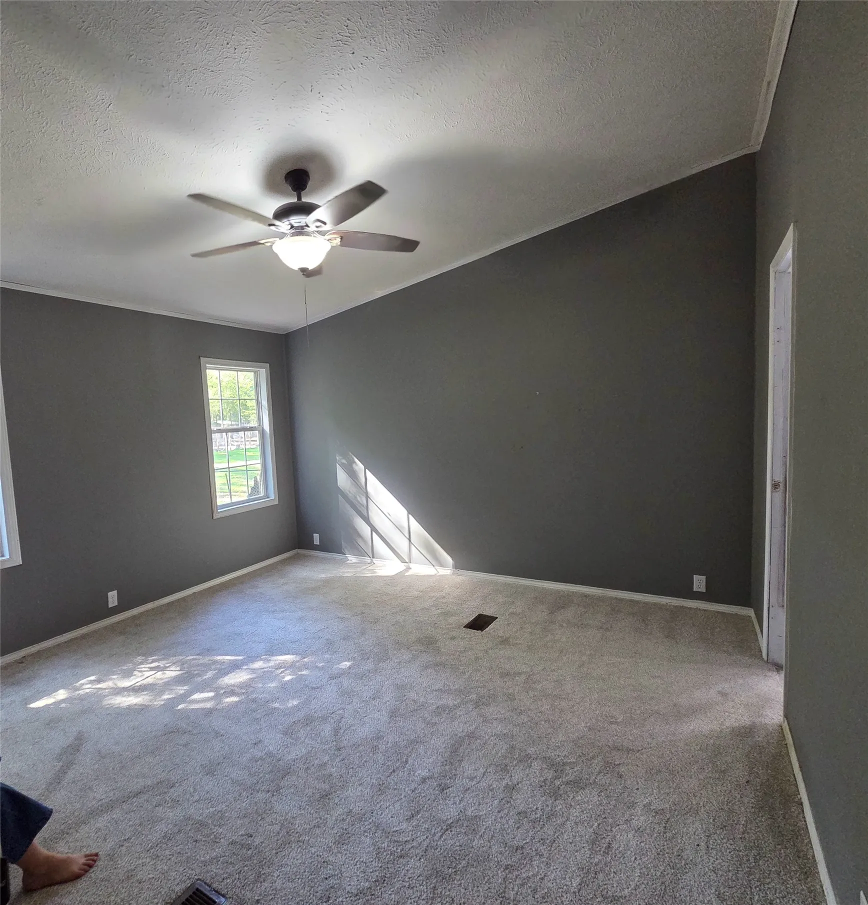 Angled ceiling with a ceiling fan, light gray wall paint, light-colored carpet flooring, and a double-hung window