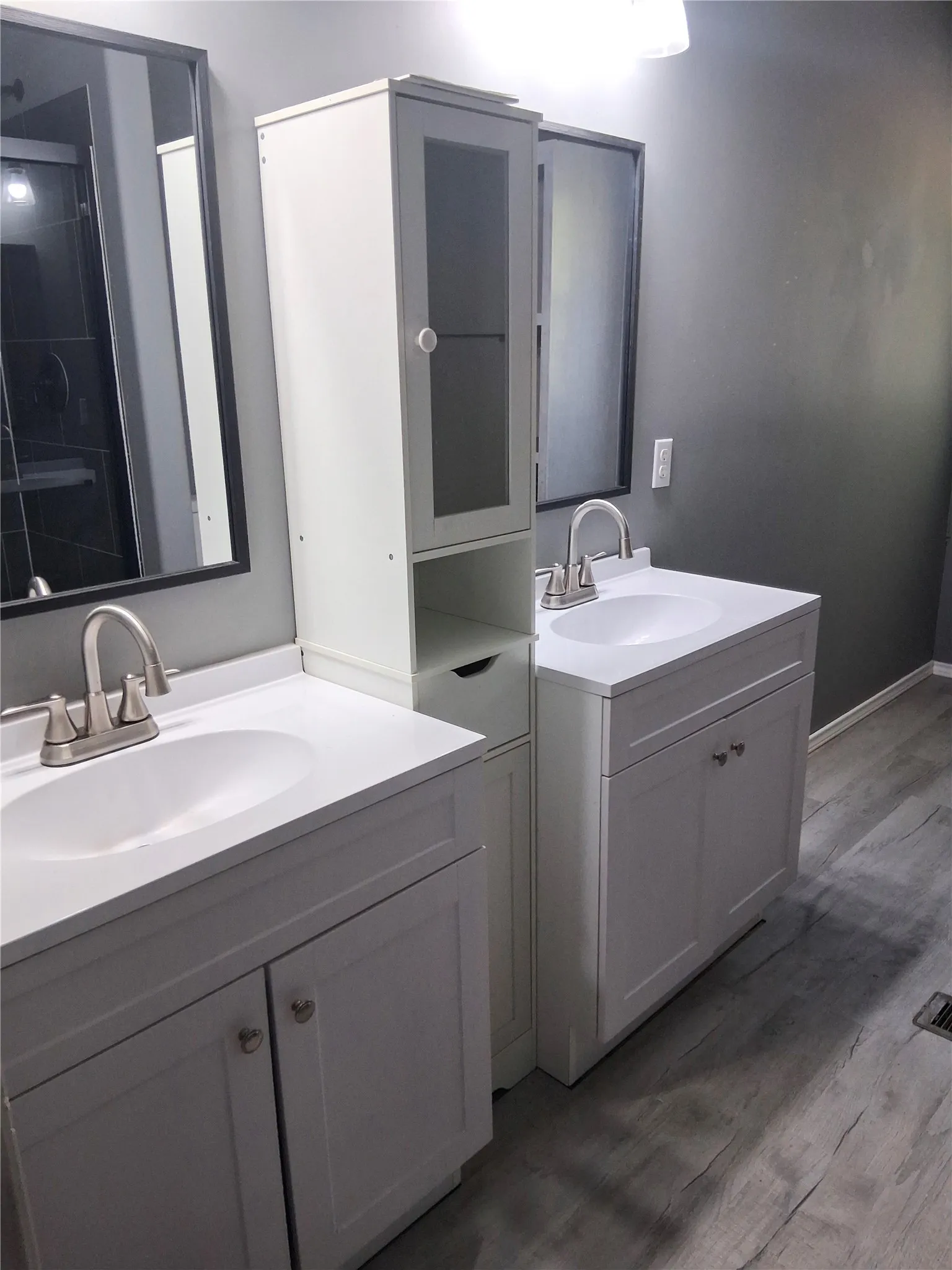 Dual vanities with white cabinetry, integrated sinks, brushed nickel faucets, and wood-finish flooring