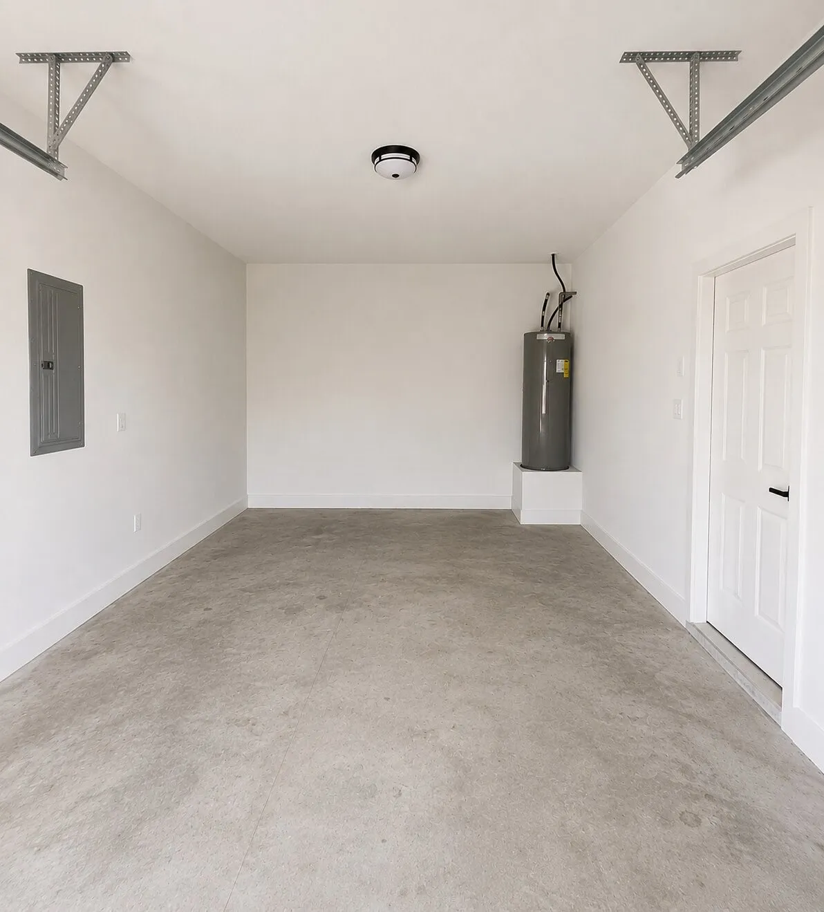 Concrete flooring, white walls, flush mount ceiling light, utility door, and water heater
