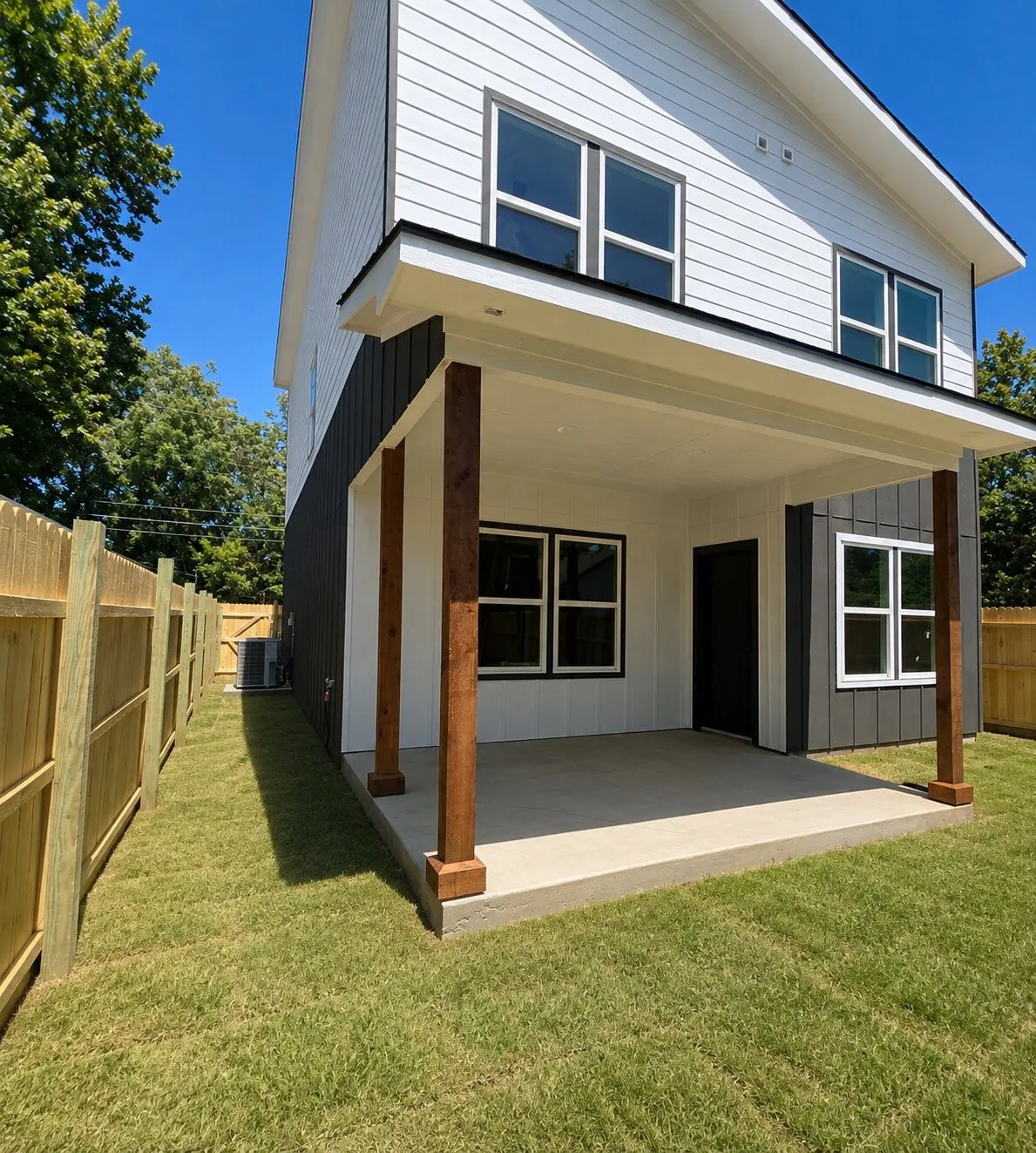 Covered patio with a concrete slab, wood support columns, and a manicured lawn