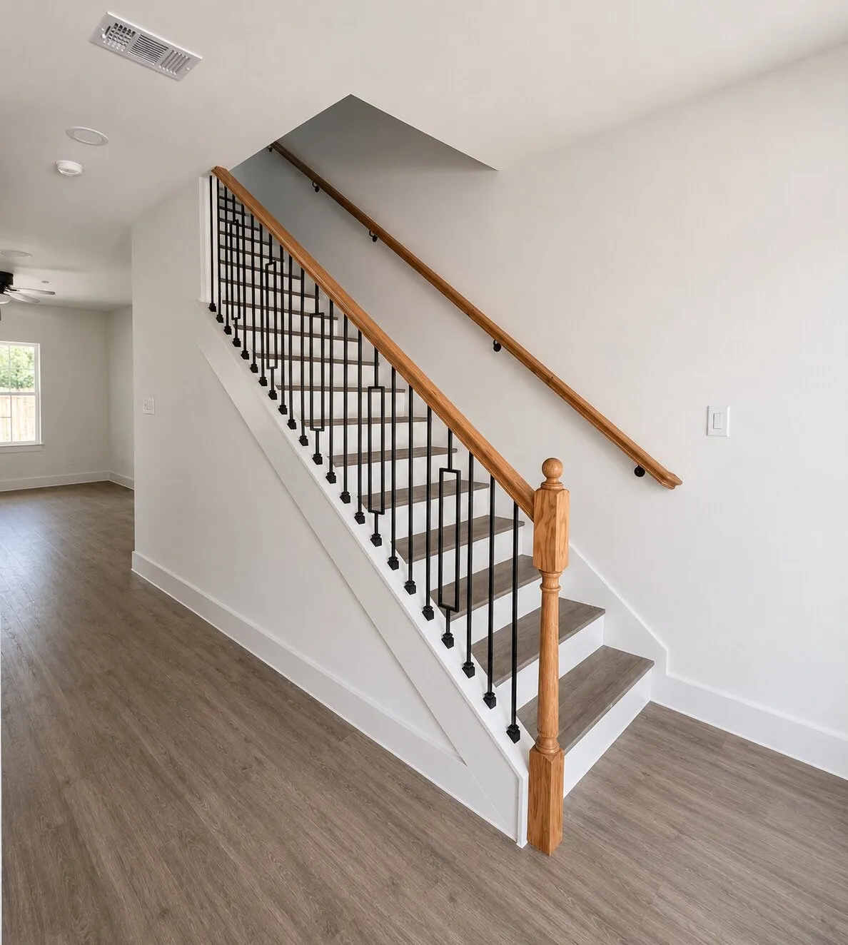 Contemporary staircase with wood-finish treads, black metal balusters, and a natural wood handrail