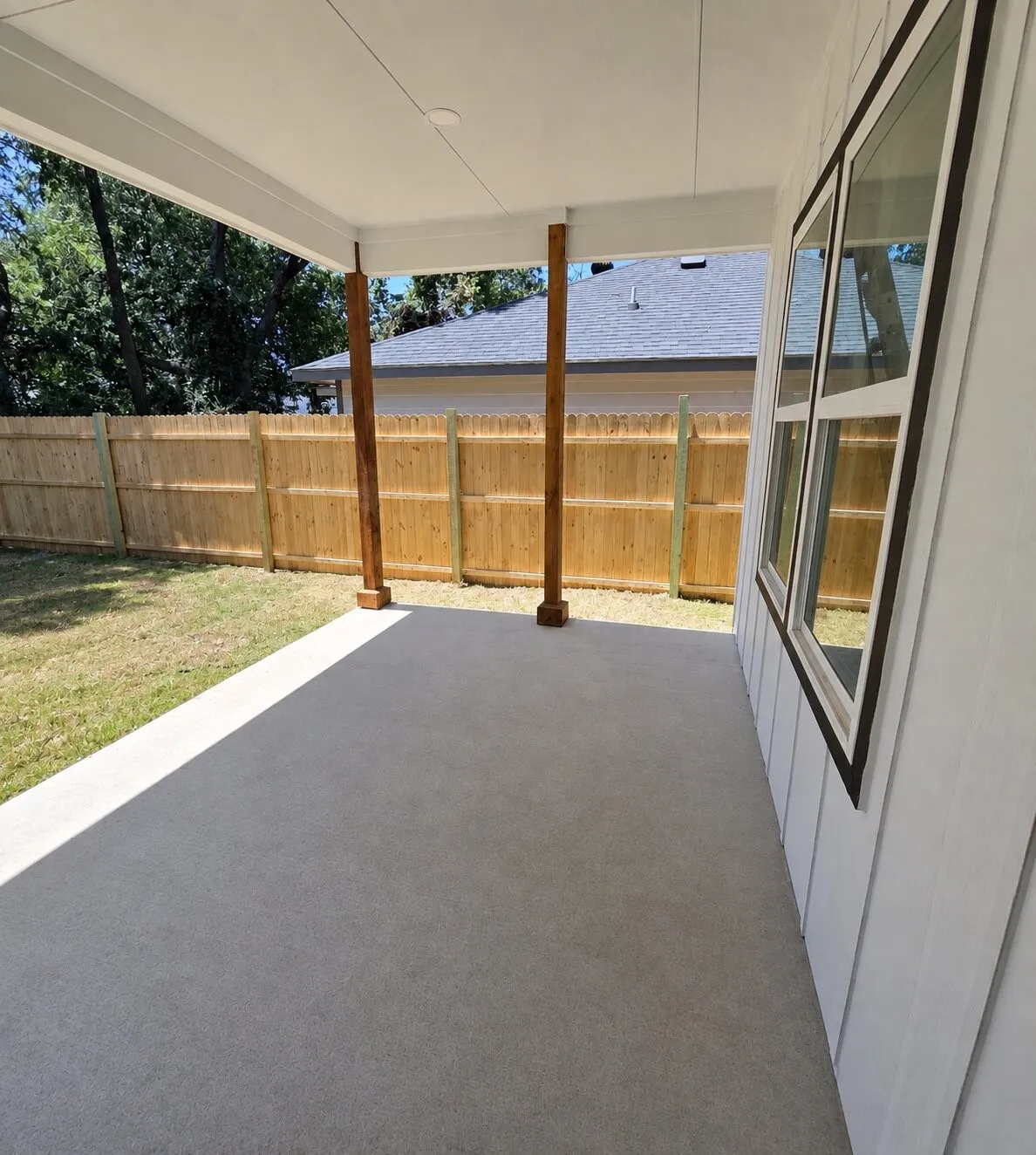 Covered outdoor patio with a concrete surface, supported by two timber posts