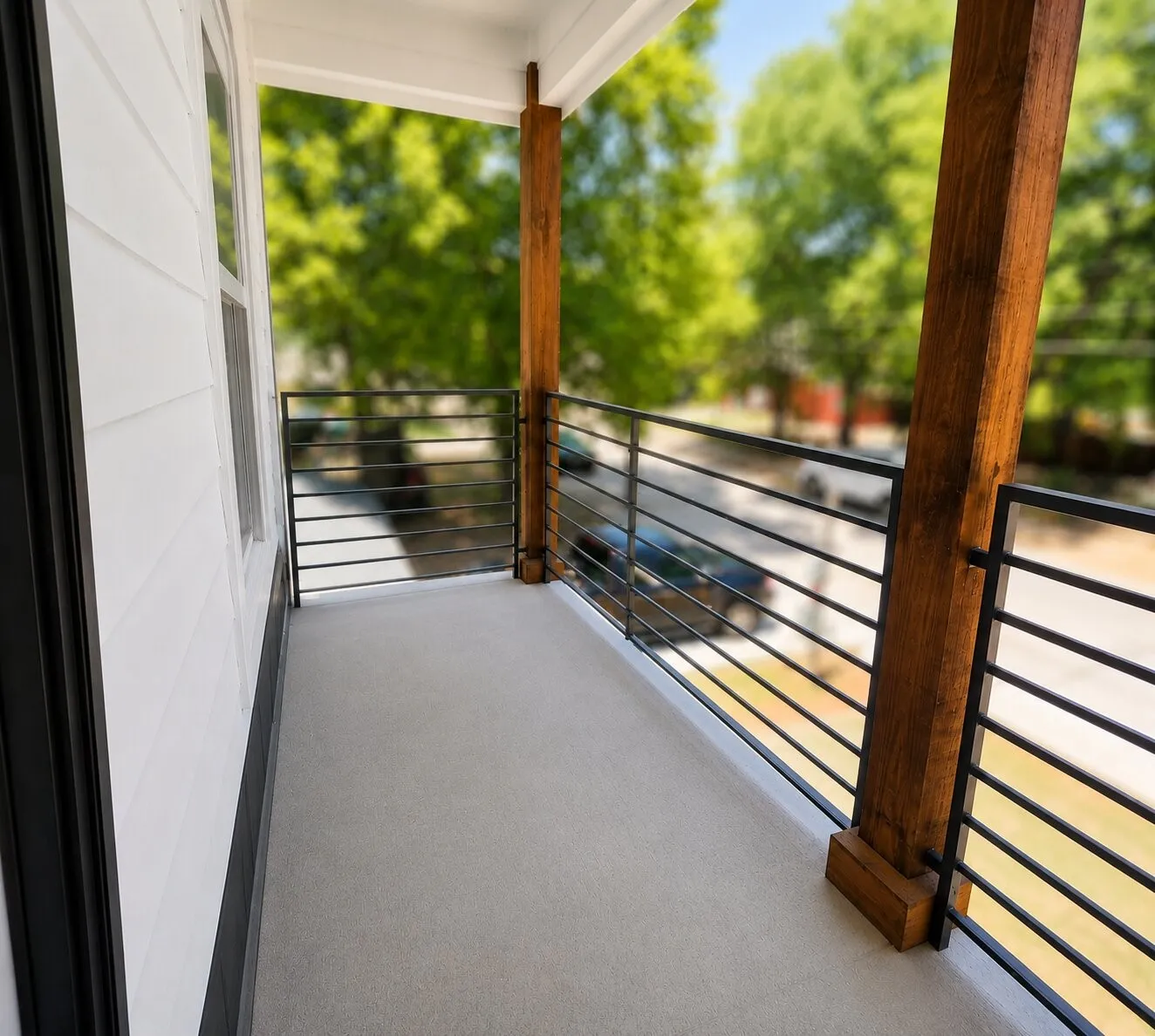 Balcony featuring a concrete surface, black metal railings, and exposed wood support beams