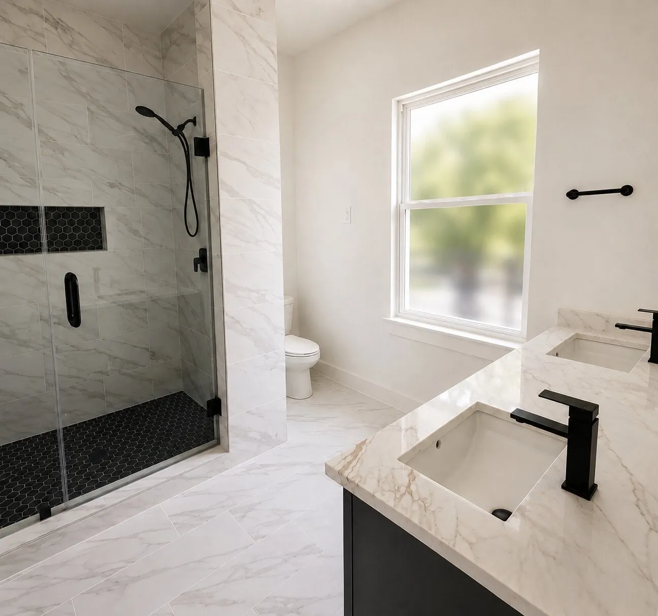 Dual vanity with undermount sinks and matte black fixtures, stone finish countertops, frameless glass shower enclosure with matte black fixtures, integrated shower niche, and hexagonal tile shower floor